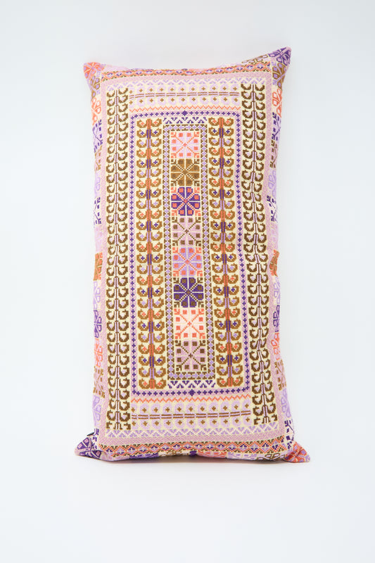 A rectangular lumbar pillow with intricate, multi-colored, geometric hand embroidery set against a white background, offering a one-of-a-kind charm: the Yasmin Hand Embroidered Pillow in Lilac and Coral by Kissweh.