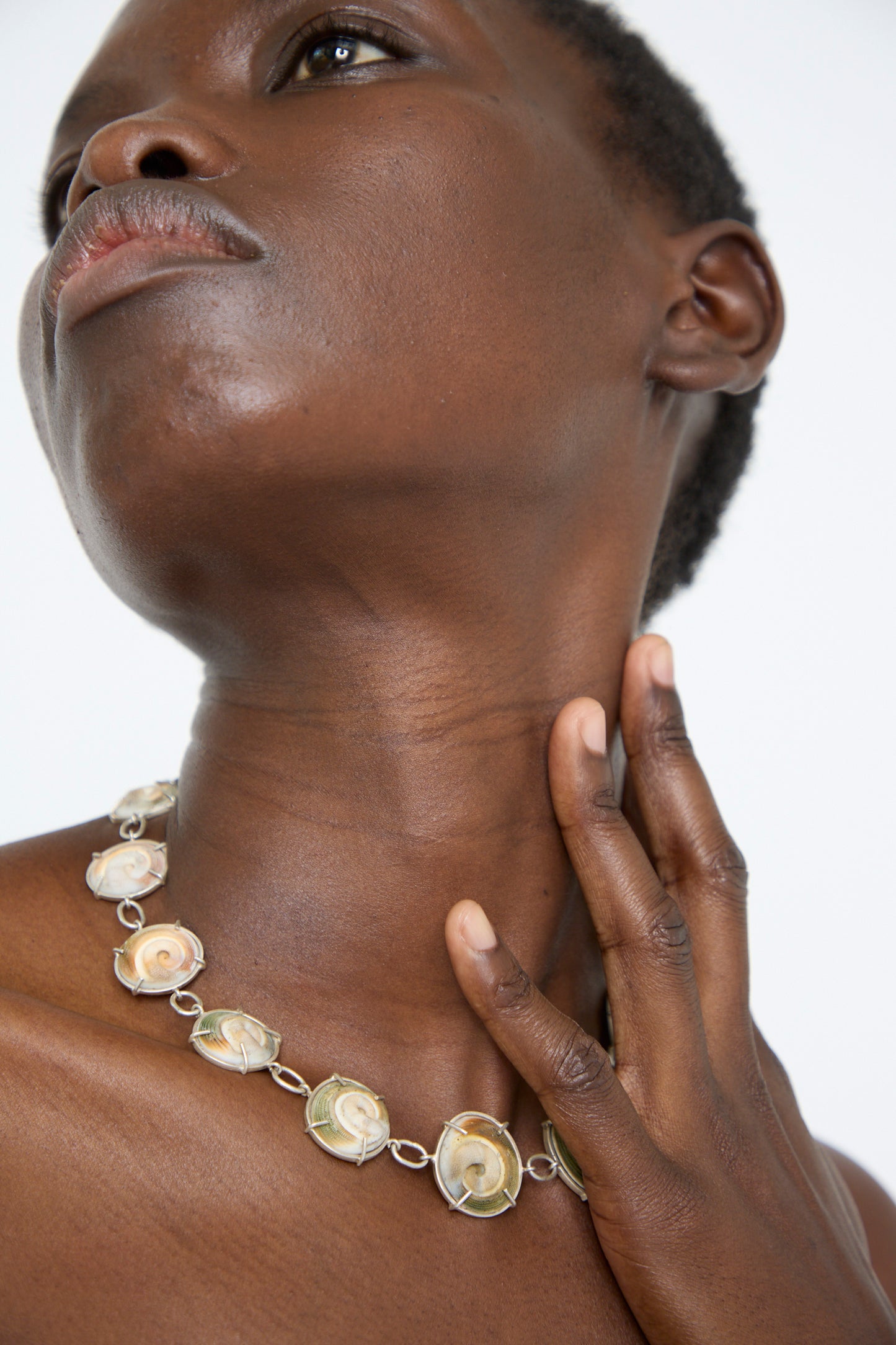 A woman wearing a handmade necklace from La Ma r. Made of  Sterling Silver and shells.