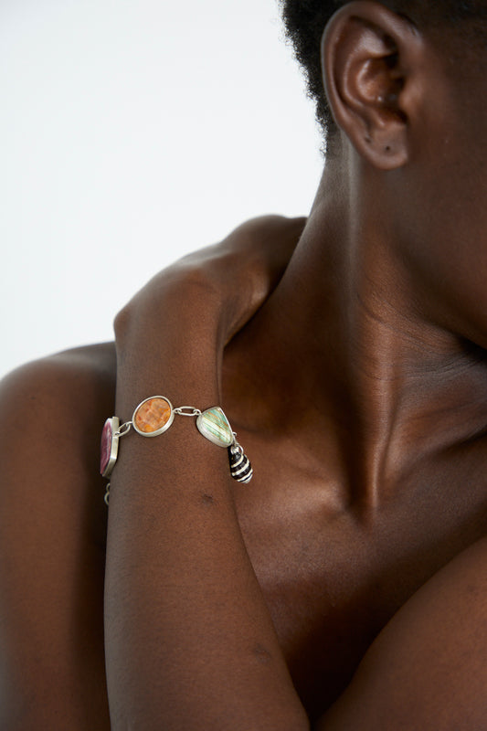 Close-up of a person wearing the Sterling Silver No. 001 Bracelet in Shell II from La Ma r, resting their hand on the side of their neck against a plain background.