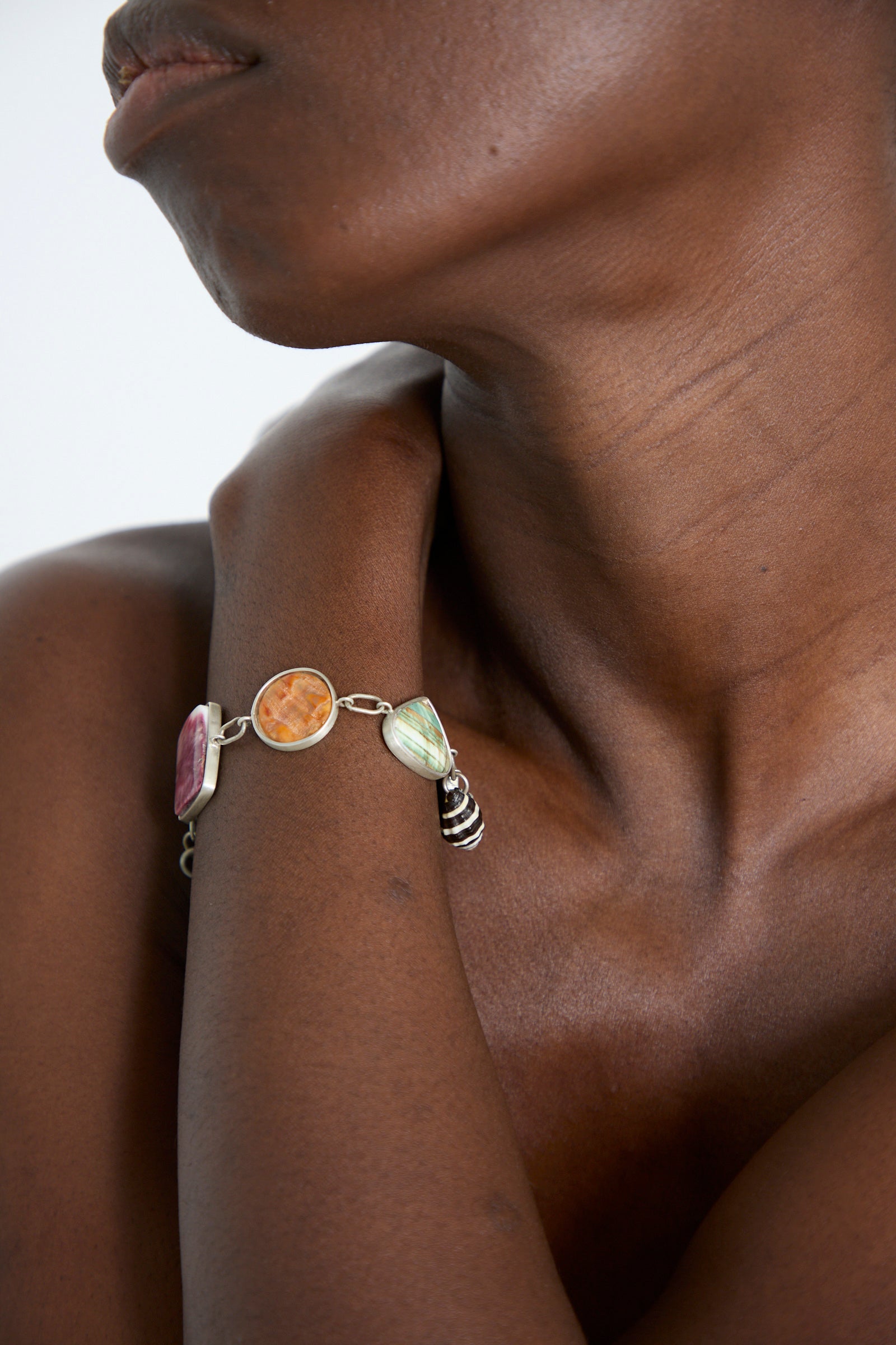 A close-up of a person with a wearing the La Mar Sterling Silver No. 001 Bracelet in Shell II, as they rest their hand on their shoulder.