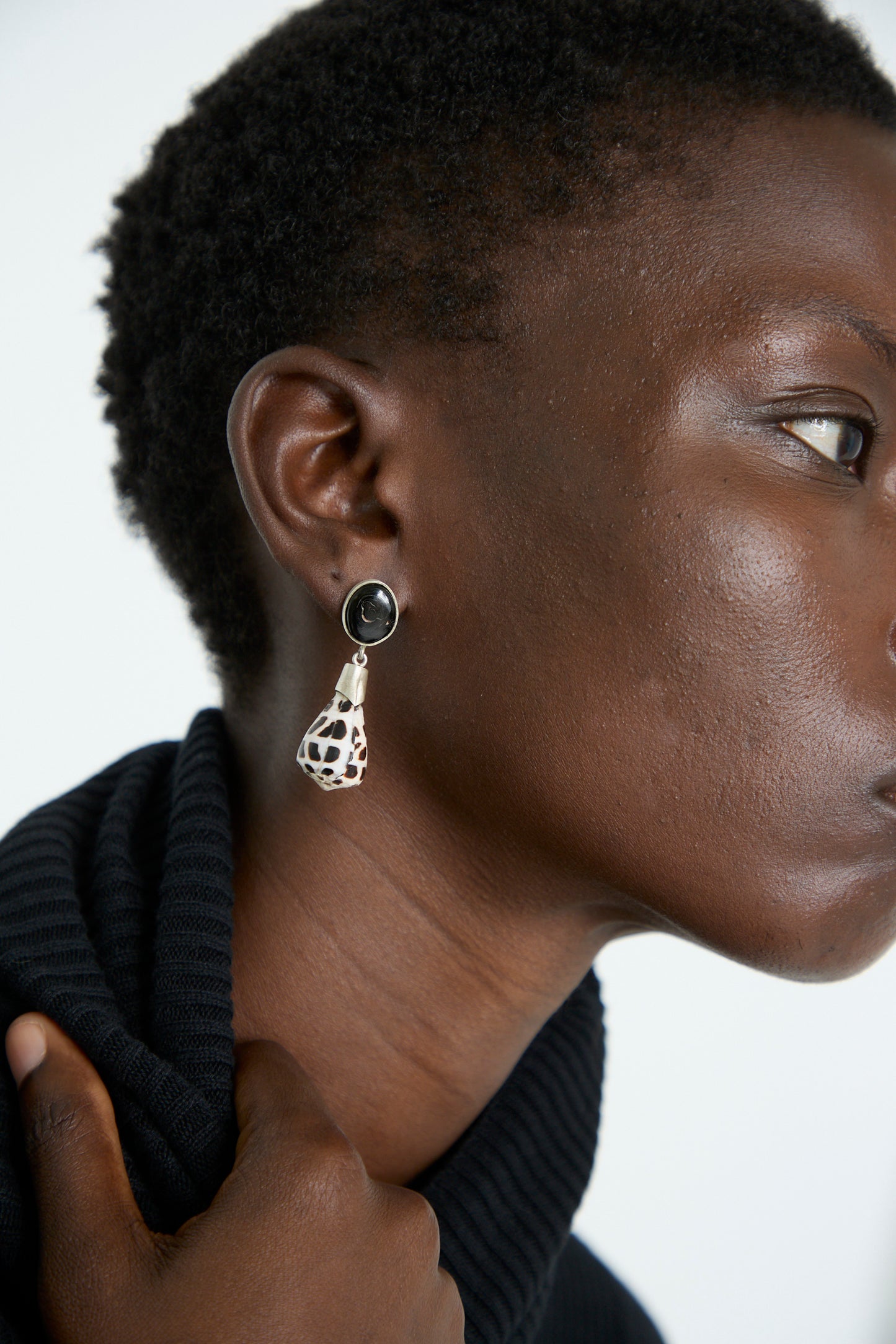 A person wearing a black turtleneck and the Sterling Silver No. 09 Earrings in Black and White Shell by La Ma r.