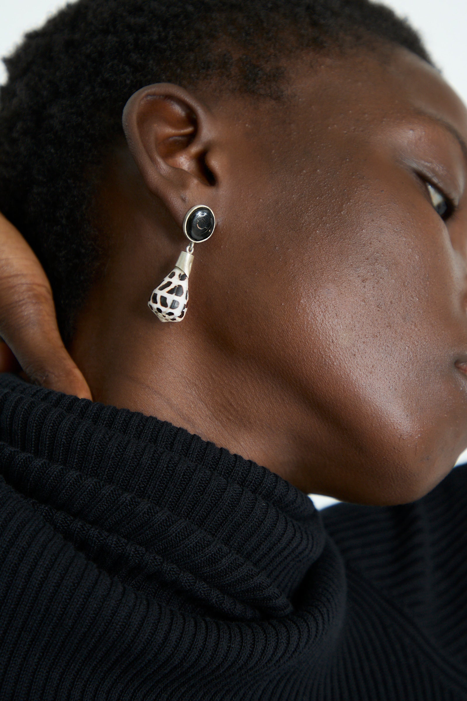 Close-up of a person wearing a black turtleneck and La Ma r's Sterling Silver No. 09 Earrings in Black and White Shell.