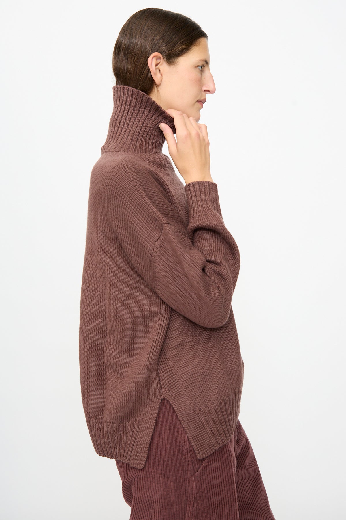 A person in profile wearing the Labo.Art Fiore Sweater in Sasso— a brown ribbed cashwool knitwear turtleneck— with matching pants, set against a plain white background.