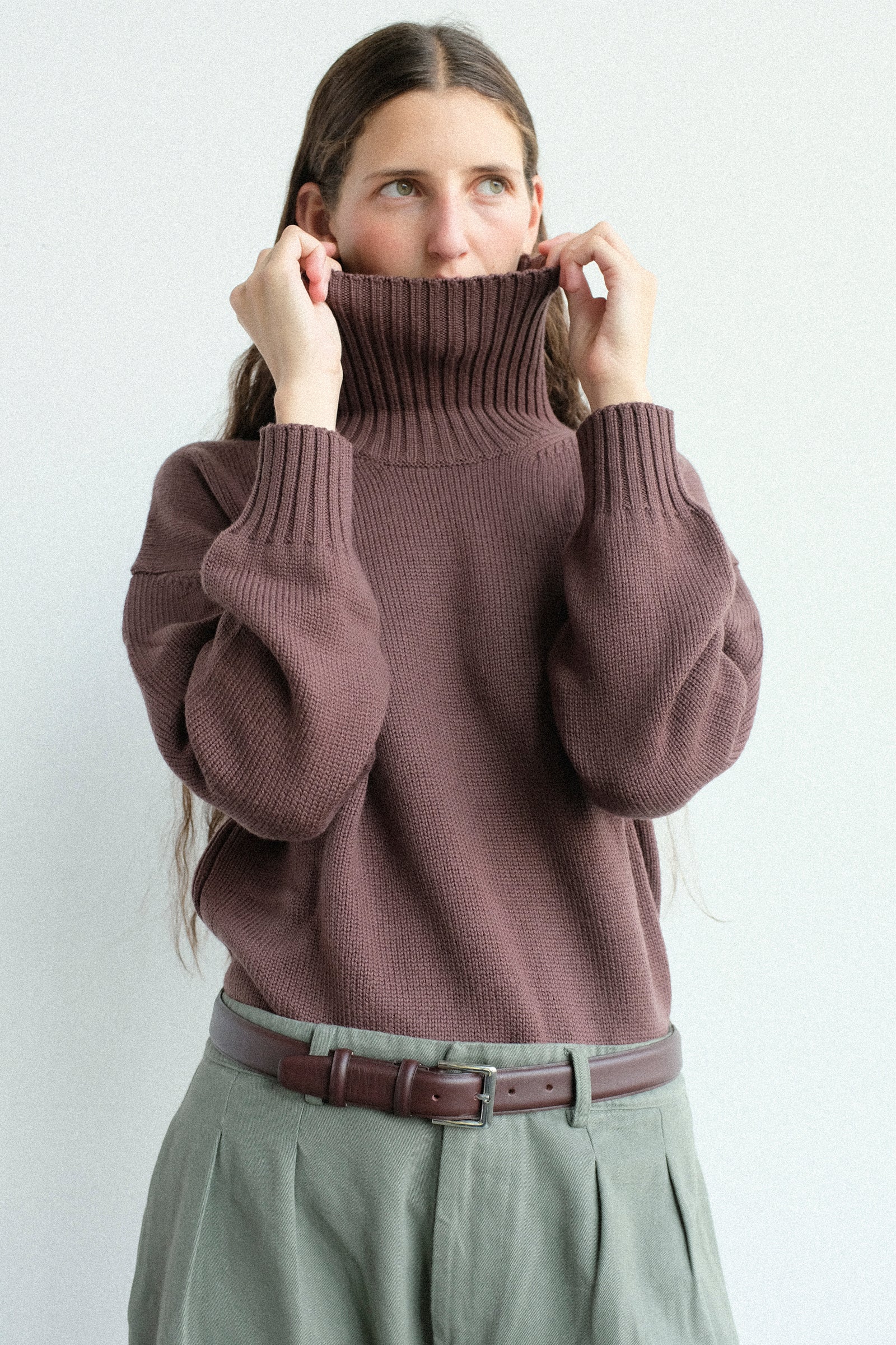 A woman wearing Labo.Art's Fiore Sweater in Sasso, and Marlon Trouser in Lichene posing against a light gray background.
