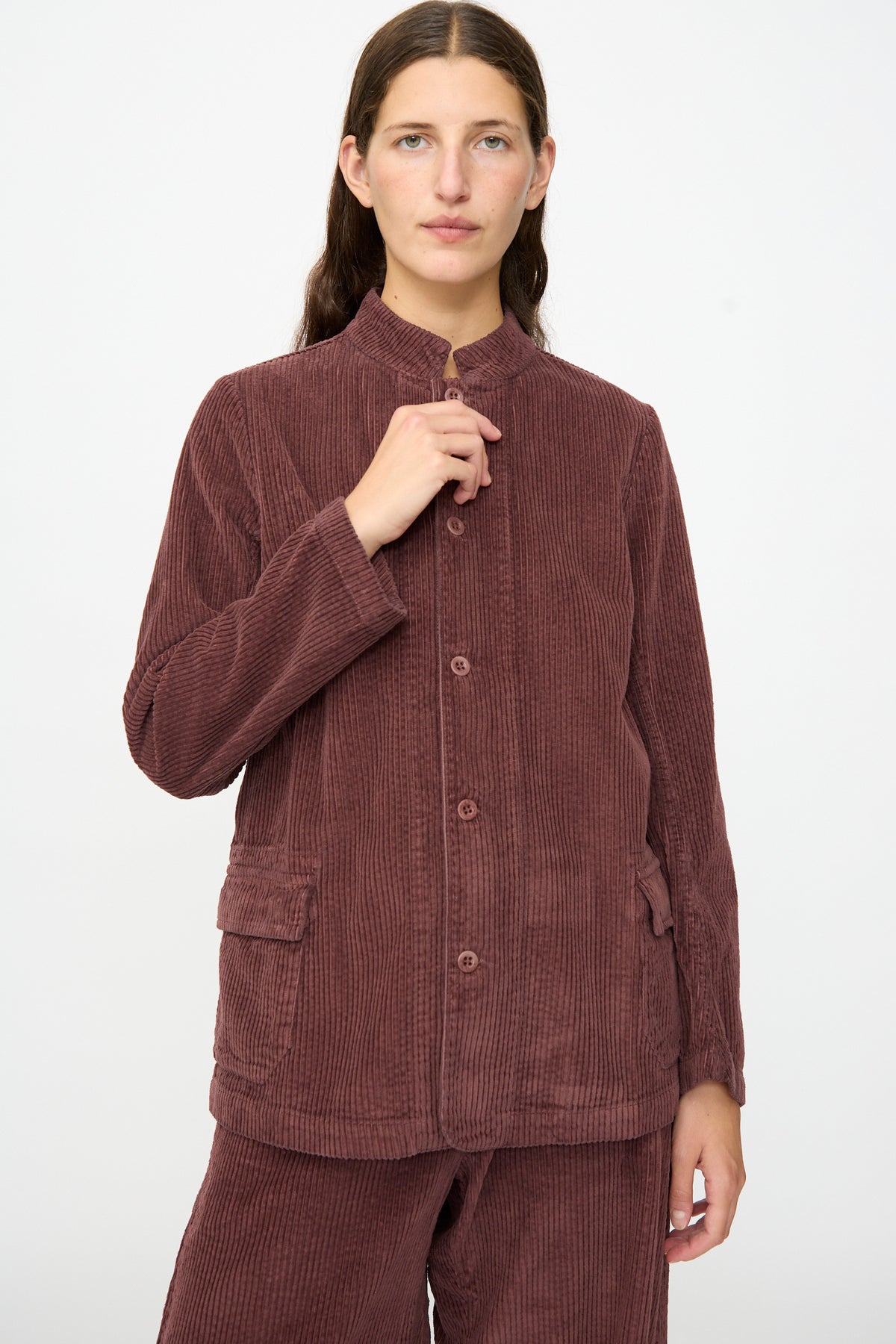A person wearing the Labo.Art Pina Jacket in Sasso—a relaxed, Italian-made cotton corduroy piece—paired with matching pants, stands against a plain white background, looking at the camera with a neutral expression.