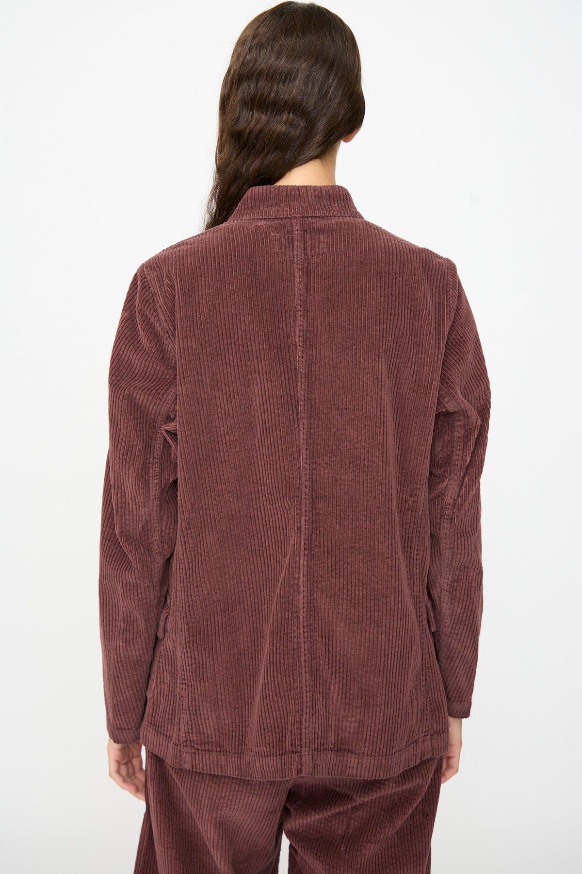 A person is shown from the back, standing against a plain white background, wearing the Labo.Art Pina Jacket in Sasso with matching maroon corduroy pants.