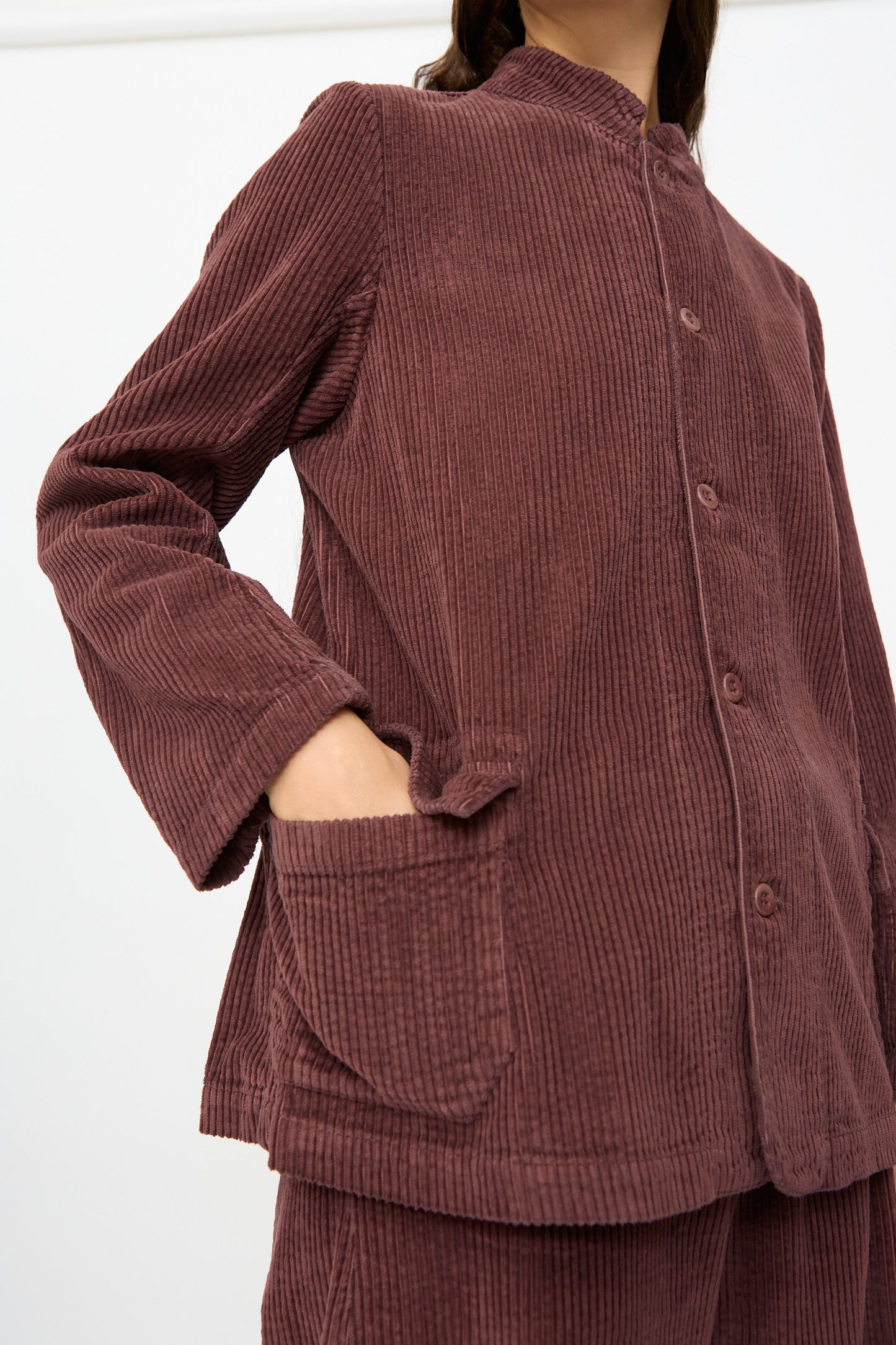 A person wearing the Labo.Art Pina Jacket in Sasso, made from relaxed cotton corduroy and paired with matching pants, has one hand in the jacket pocket and is shown from shoulders to mid-thigh.