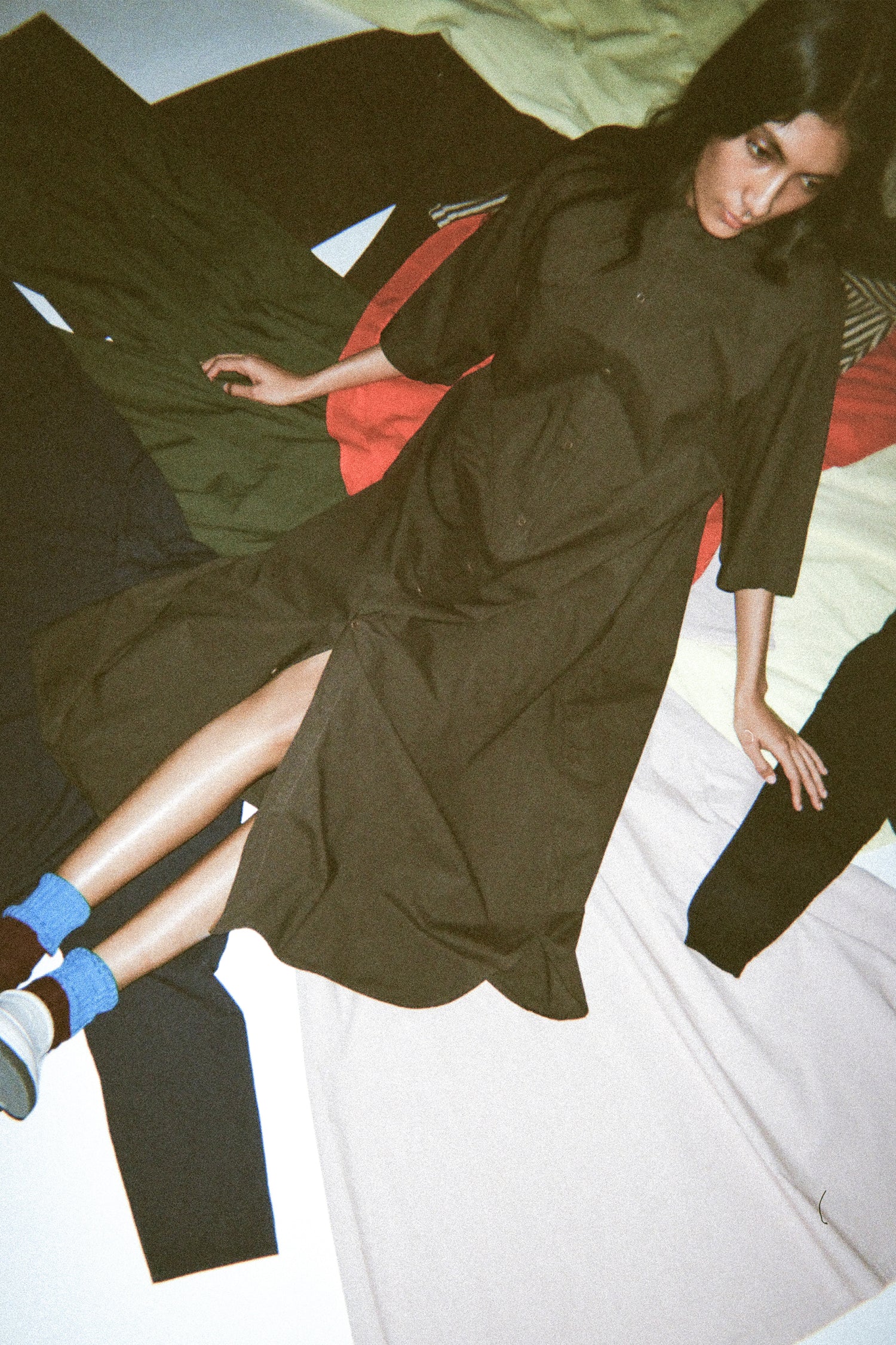 A woman wearing Labo.Art's Cotton Acca Dress in Maron and sitting on the SS26 spread out on the floor.