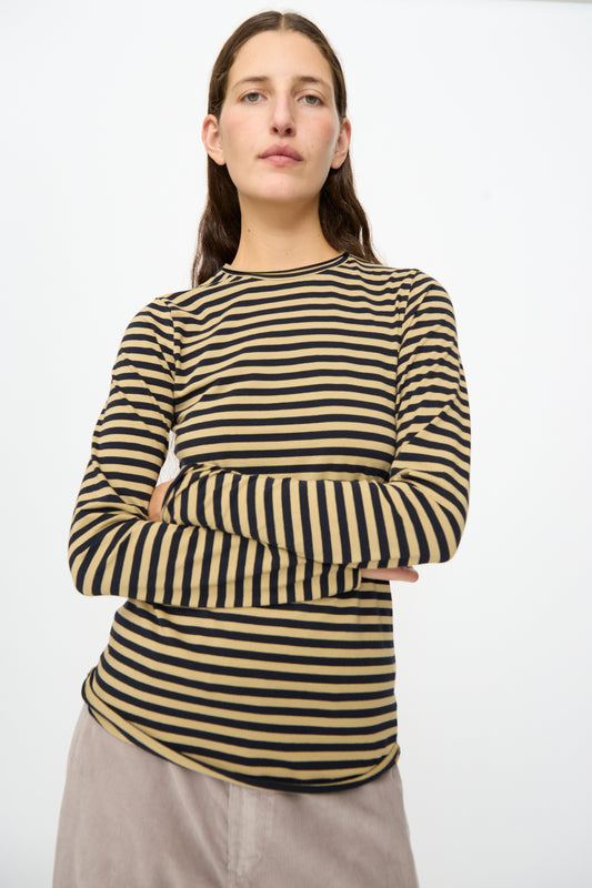A person stands with arms crossed against a plain white background, wearing the Labo.Art Striped Jersey Basic Longsleeve in Fennec. This slim fit shirt offers a classic cotton crewneck design for all-day comfort and effortless style.