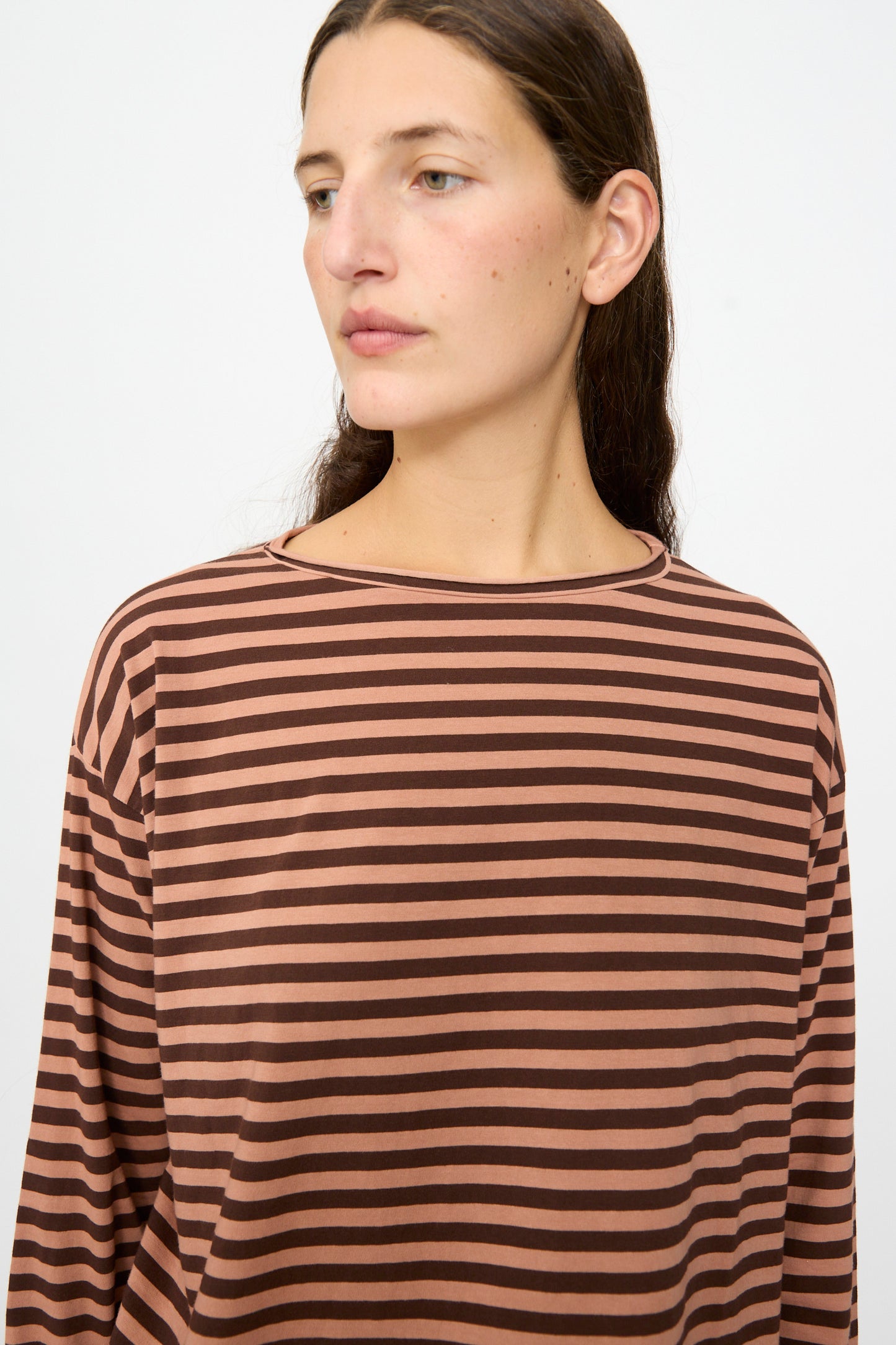 A person with long brown hair wears the Labo.Art Striped Jersey Lola Sweater in Canyon—a relaxed fit, brown and black striped long sleeve top—while looking slightly to the side against a plain background.