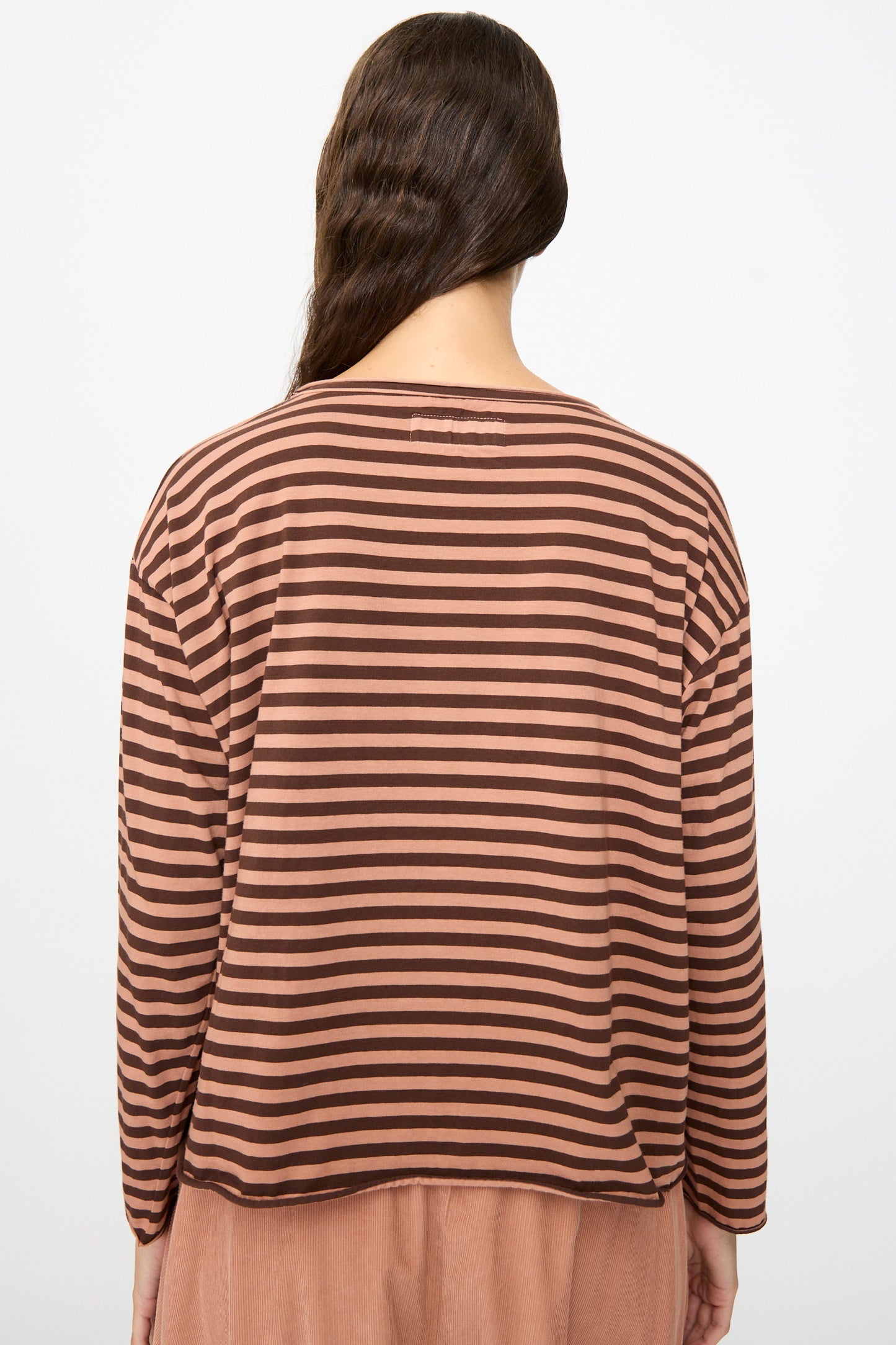 A person with long brown hair, seen from behind, wears the Labo.Art Striped Jersey Lola Sweater in Canyon—a relaxed fit, long-sleeve top featuring horizontal brown and dark brown stripes.