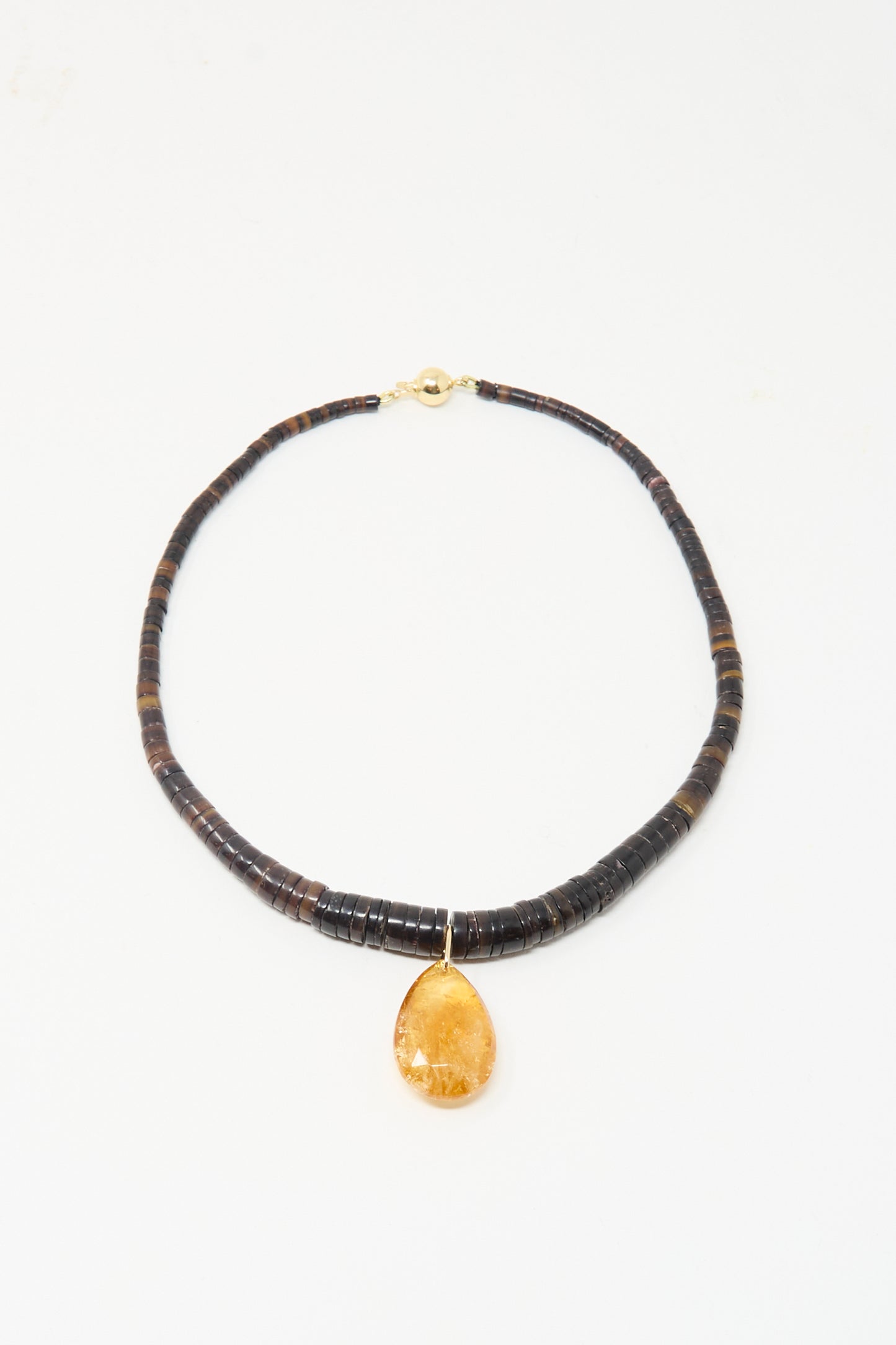 The Drop Collar in Sunset by Laoli features dark round beads and a large teardrop-shaped amber pendant, handmade in Paris and shown on a simple white background.