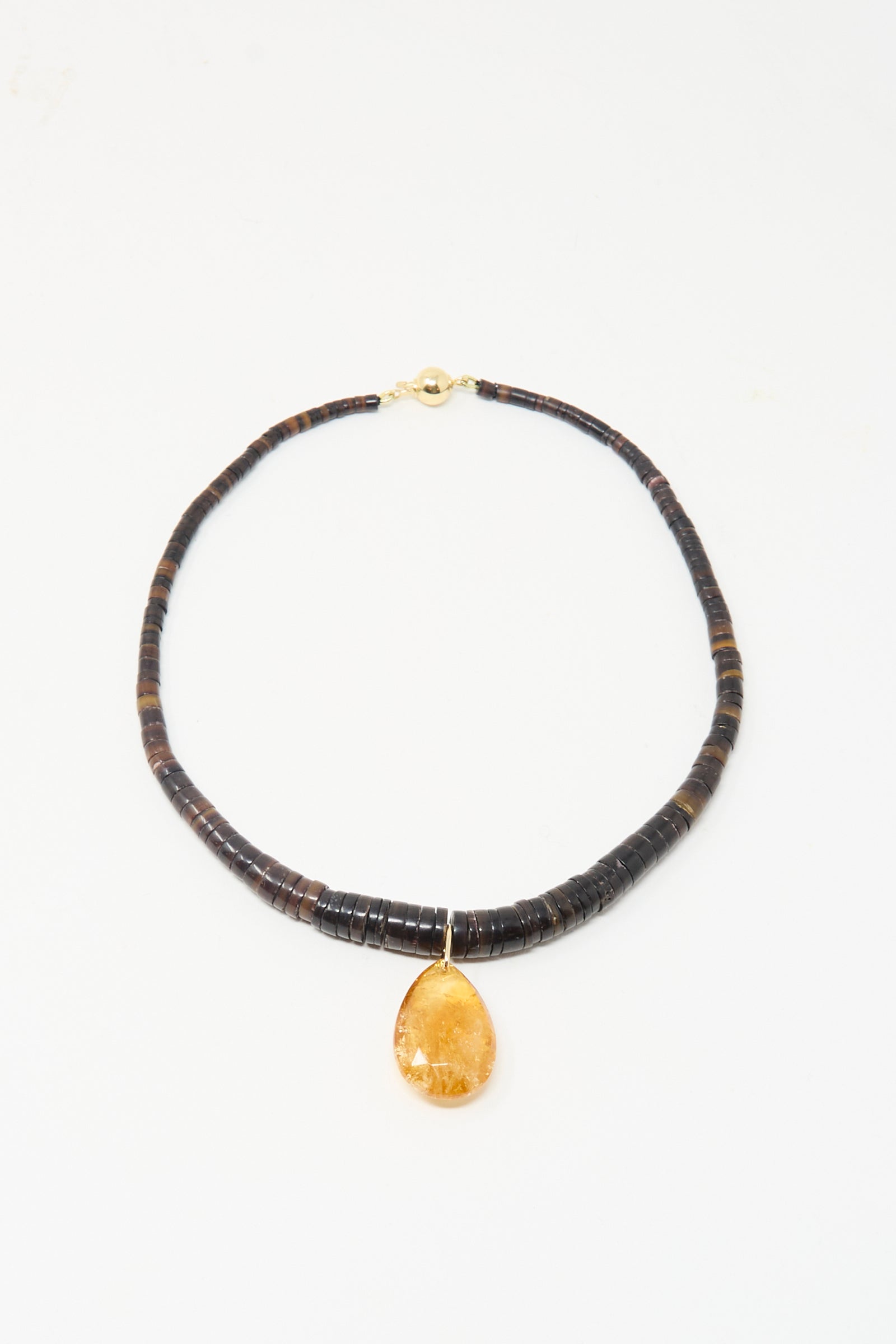 The Drop Collar in Sunset by Laoli features dark round beads and a large teardrop-shaped amber pendant, handmade in Paris and shown on a simple white background.