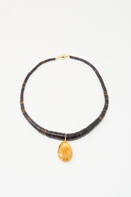 The Drop Collar in Sunset by Laoli features dark round beads and a large teardrop-shaped amber pendant, handmade in Paris and shown on a simple white background.
