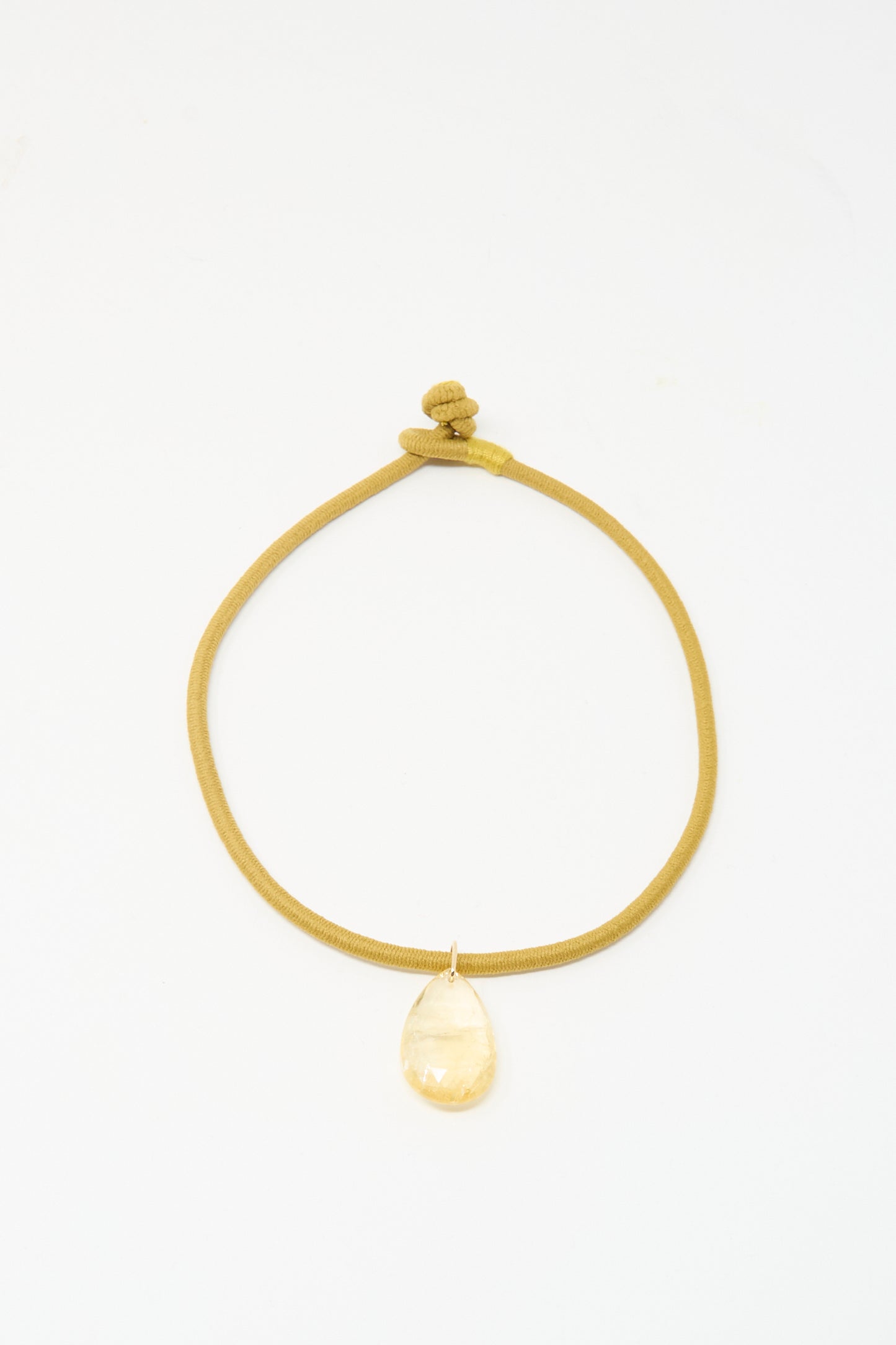 The Drop Cord in Tan and Citrine by Laoli is a handmade necklace from Paris, featuring a gold cord with knot closure and a large teardrop-shaped citrine pendant, shown against a white background.