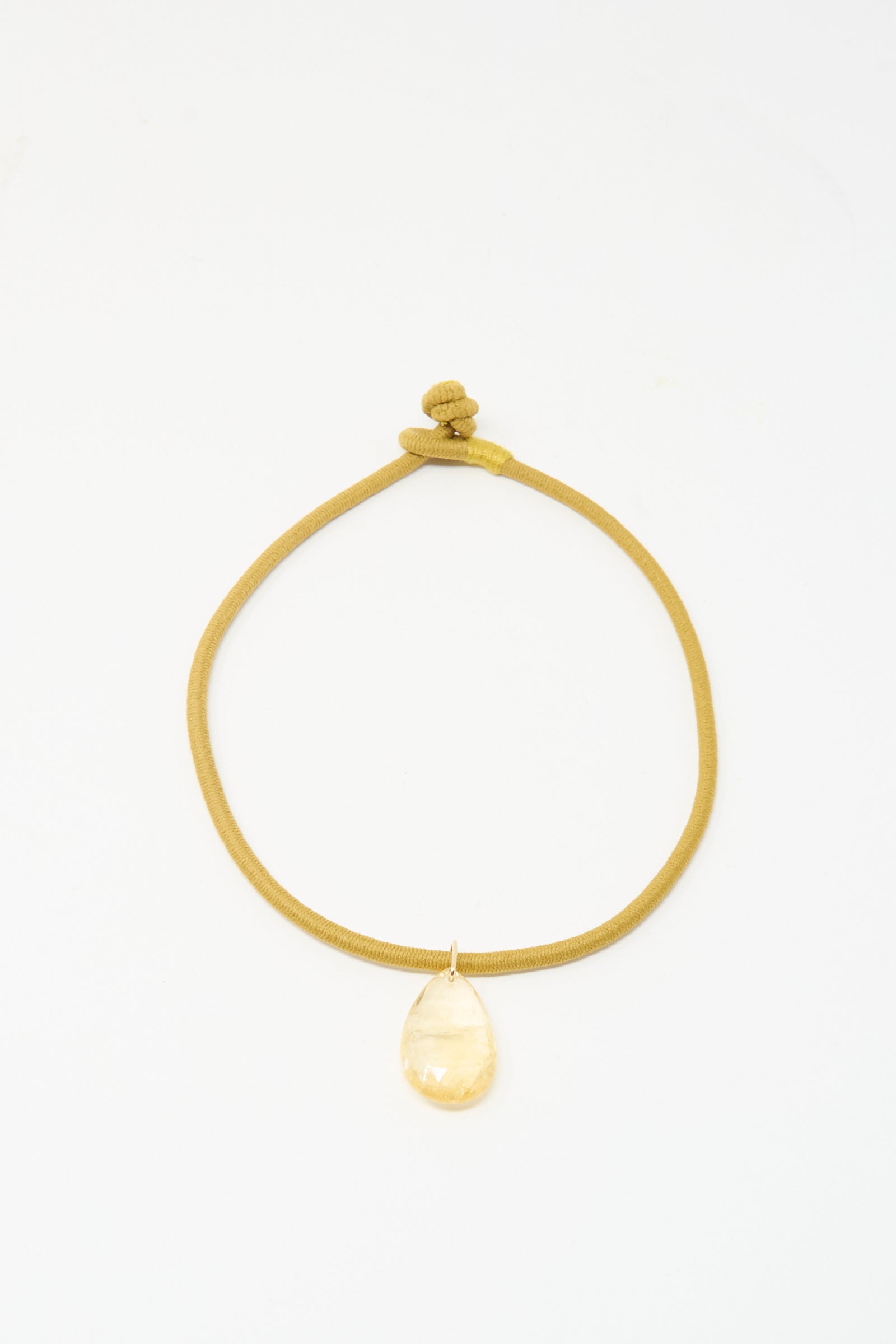 The Drop Cord in Tan and Citrine by Laoli is a handmade necklace from Paris, featuring a gold cord with knot closure and a large teardrop-shaped citrine pendant, shown against a white background.