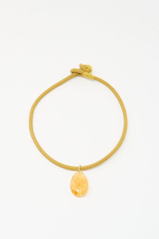 The Drop Cord in Tan and Sunset Citrrine by Laoli features a looped, handmade mustard-yellow cord and a faceted amber teardrop pendant.