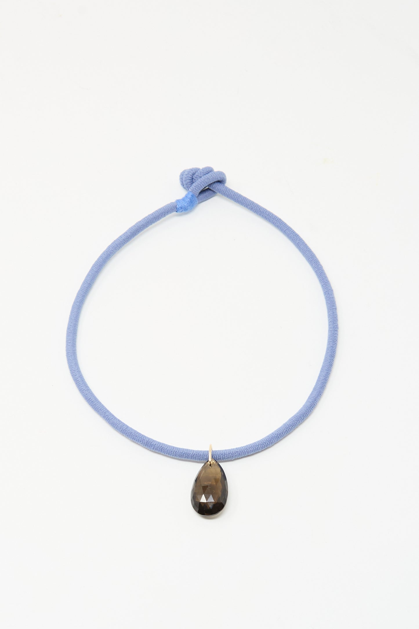 The Petite Drop Cord in Blue and Smoky Quartz by Laoli is a handmade Parisian necklace with a light blue cord, knotted design, and a single teardrop-shaped smoky quartz pendant, shown on a plain white background.