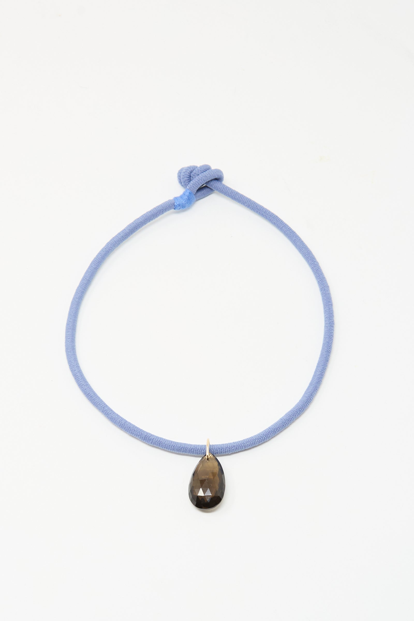 The Petite Drop Cord in Blue and Smoky Quartz by Laoli is a handmade Parisian necklace with a light blue cord, knotted design, and a single teardrop-shaped smoky quartz pendant, shown on a plain white background.