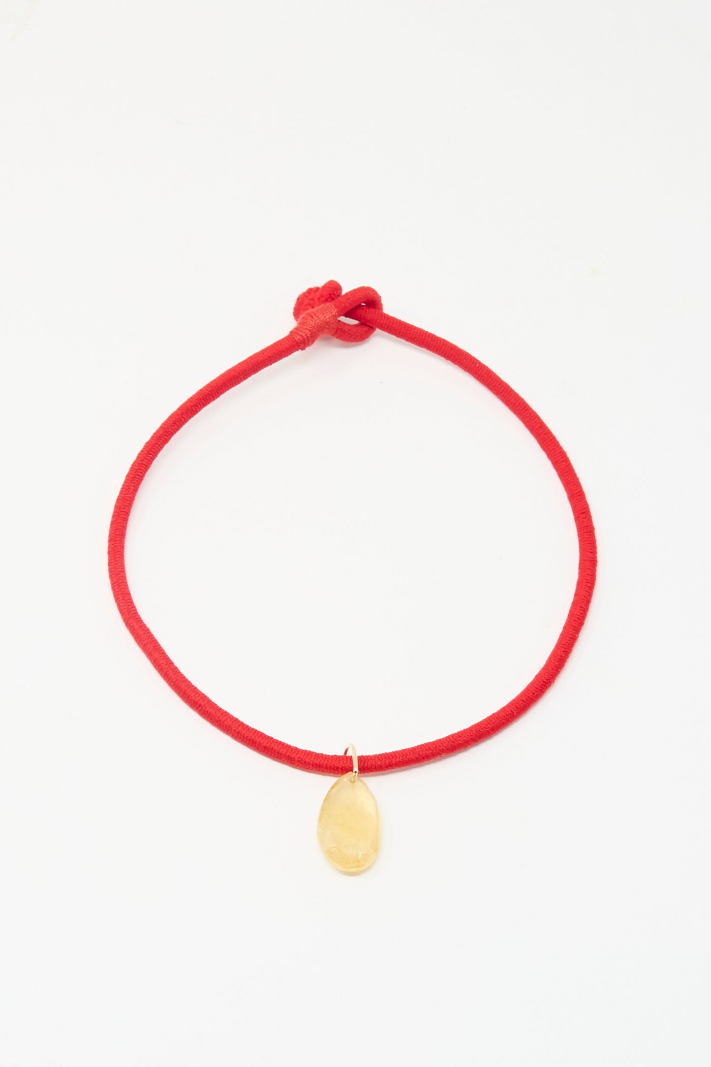 The Petite Drop Cord in Red and Citrine by Laoli is a simple red bracelet with a single oval citrine-like stone, shown on a white background.