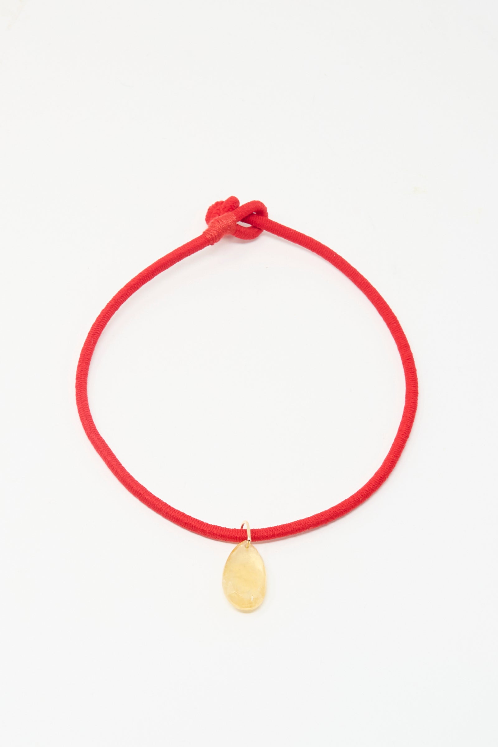 The Petite Drop Cord in Red and Citrine by Laoli is a simple red bracelet with a single oval citrine-like stone, shown on a white background.