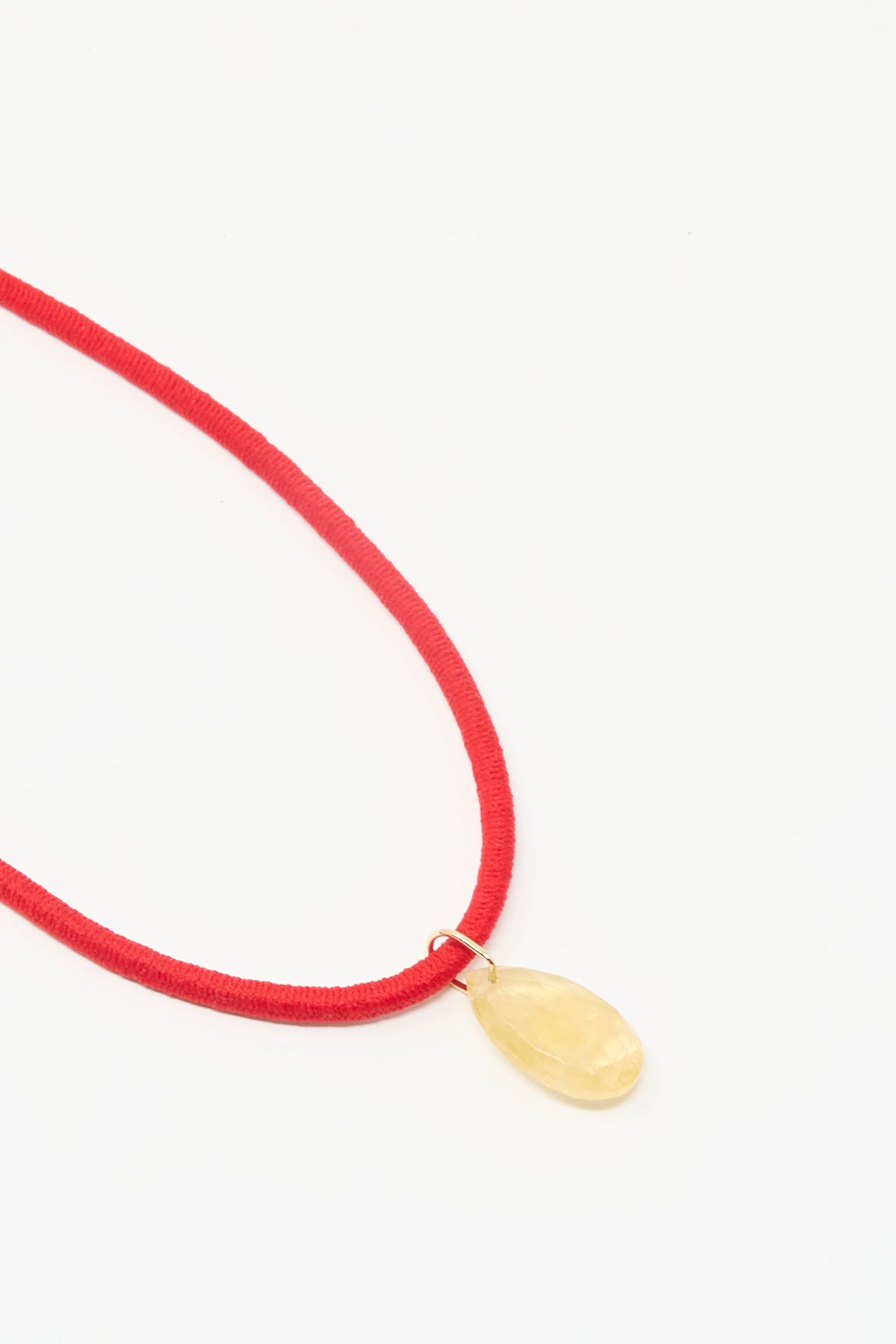 Laoli’s The Petite Drop Cord in Red and Citrine is a handmade necklace with a teardrop-shaped yellow citrine pendant on a red cord, displayed against a white background.