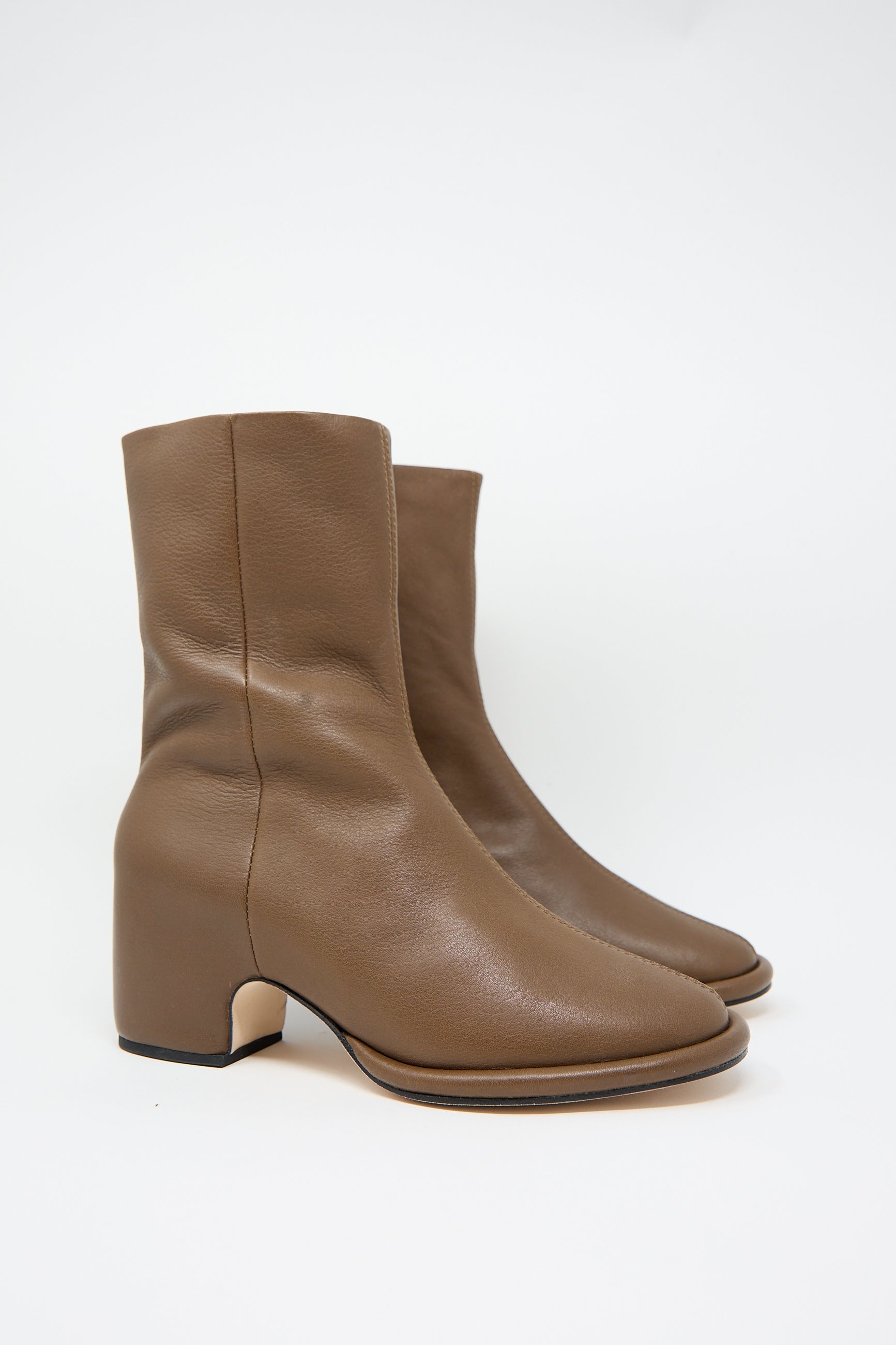 The "Arch Boot in Brown" by Lauren Manoogian is a pair of ankle-length boots featuring a block heel, crafted from vegetable tanned leather with a side zip closure. They are photographed against a plain white background.