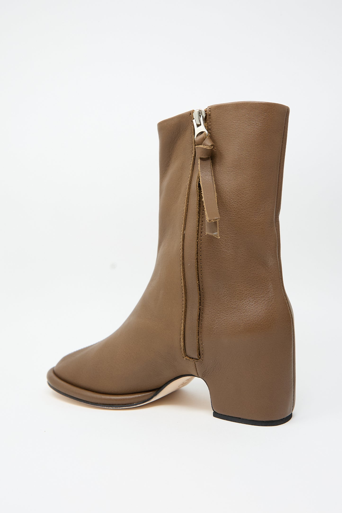 The Arch Boot in Brown by Lauren Manoogian showcases a central split-toe design and a convenient side zip closure. Expertly handcrafted in Peru using vegetable tanned leather, these boots exude elegance against a white background.