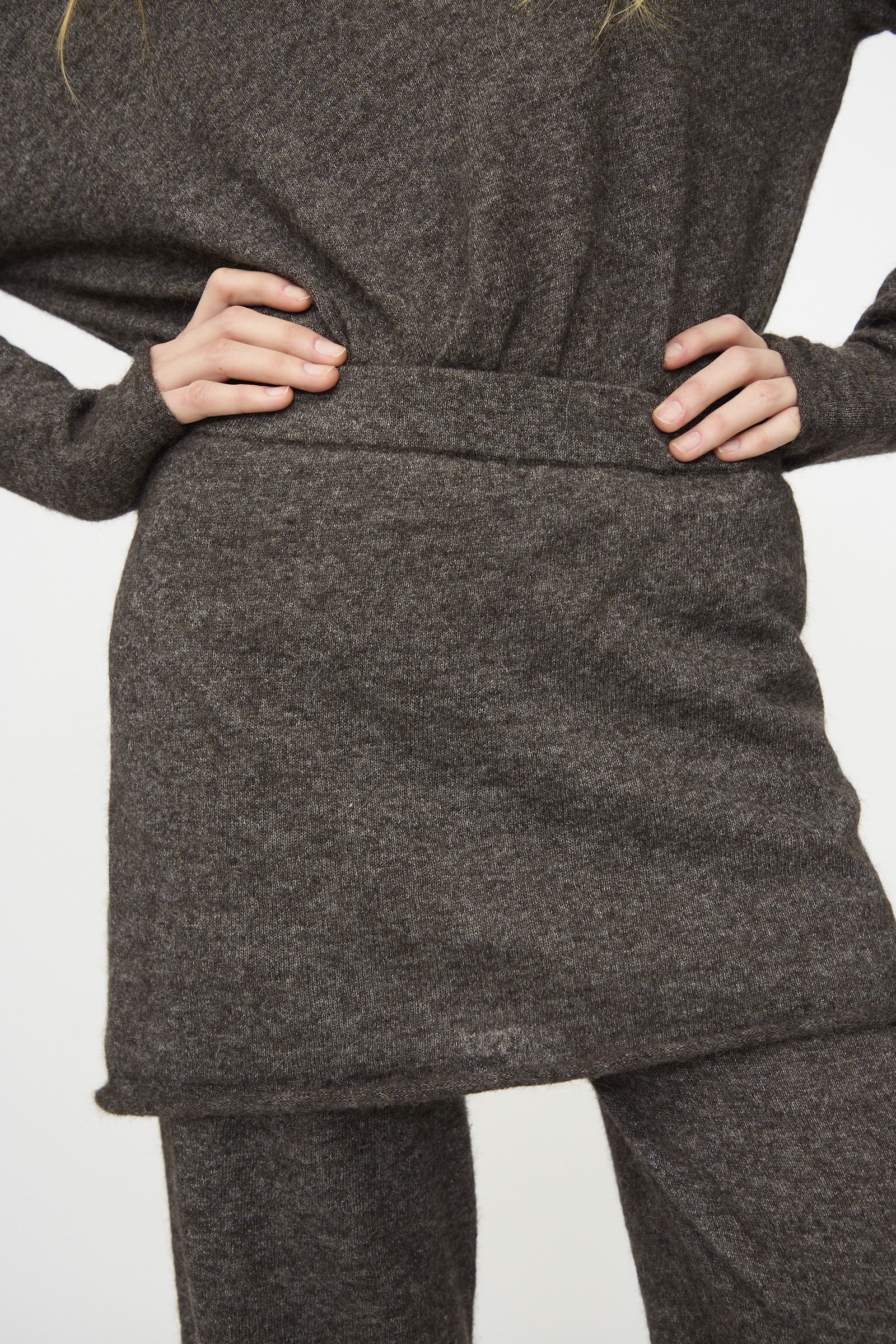 Person wearing a brown knit sweater, matching skirt, and Lauren Manoogian Askew Layer Pants in Blackened; hands on hips, midsection view against a plain background.