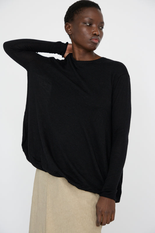 A model in a black oversized Balloon Pullover by Lauren Manoogian and a beige skirt poses against a plain white background.