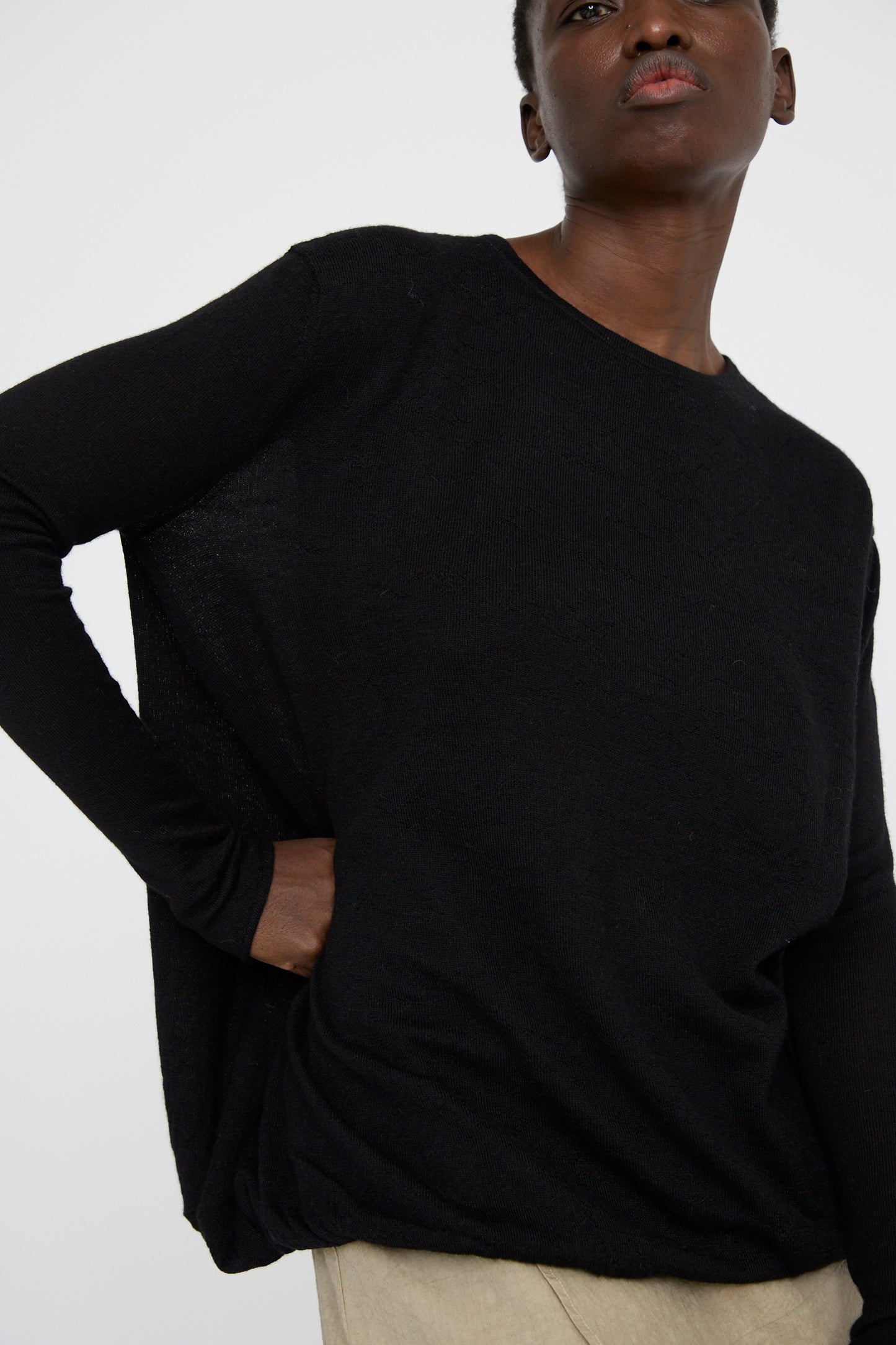 A person in an oversized Balloon Pullover in Black by Lauren Manoogian stands with one hand on their hip against a plain background.