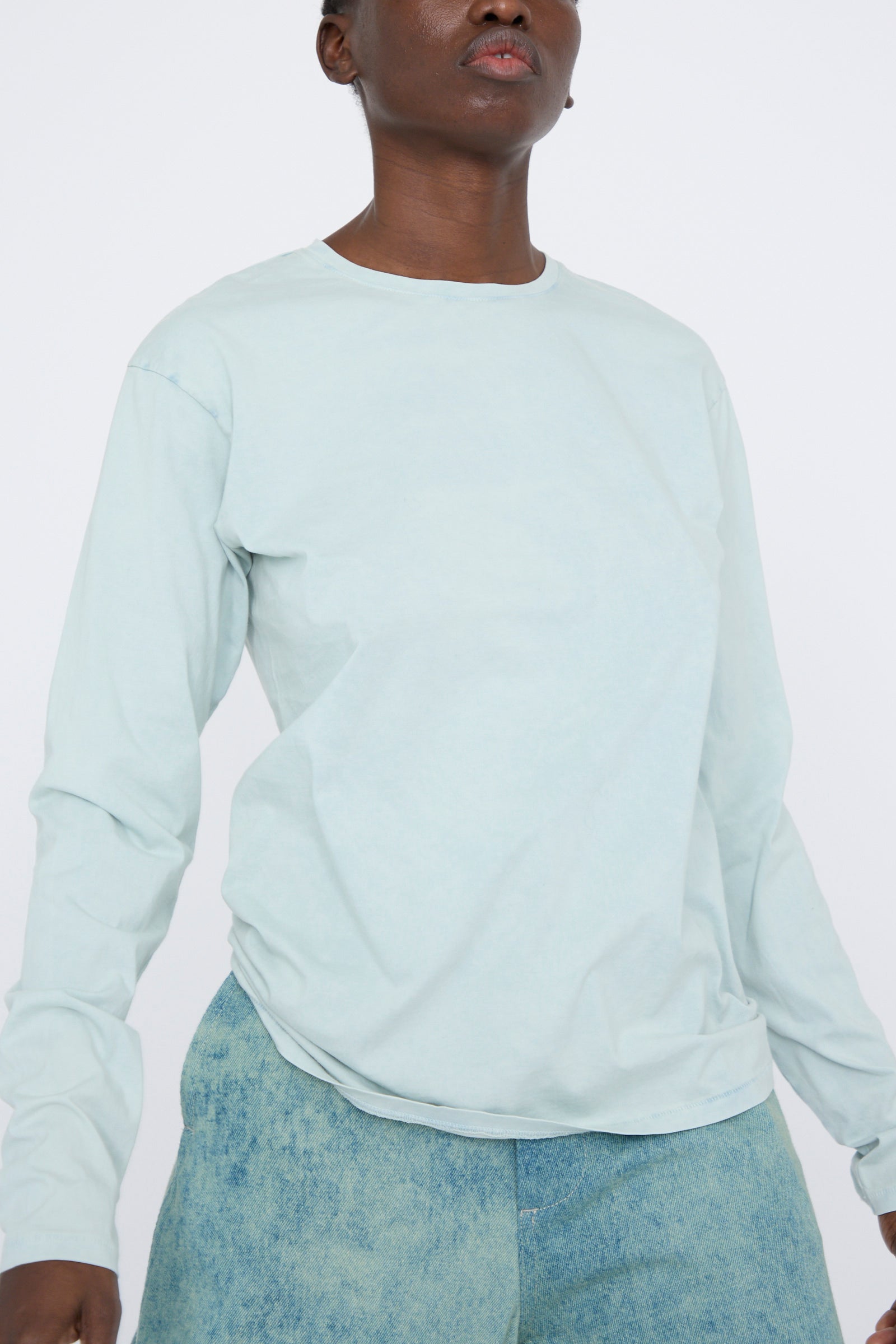 Person wearing a Bias Long Sleeve Tee in Acid by Lauren Manoogian and relaxed fit blue jeans against a plain background.