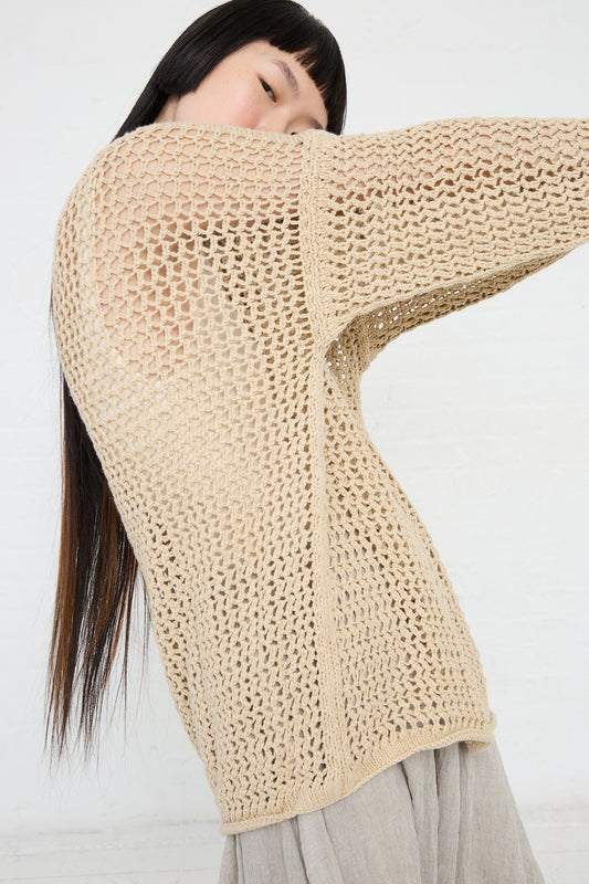 Woman wearing an oversized Lauren Manoogian Big Net Pullover in Jute with her arm raised, against a white background.