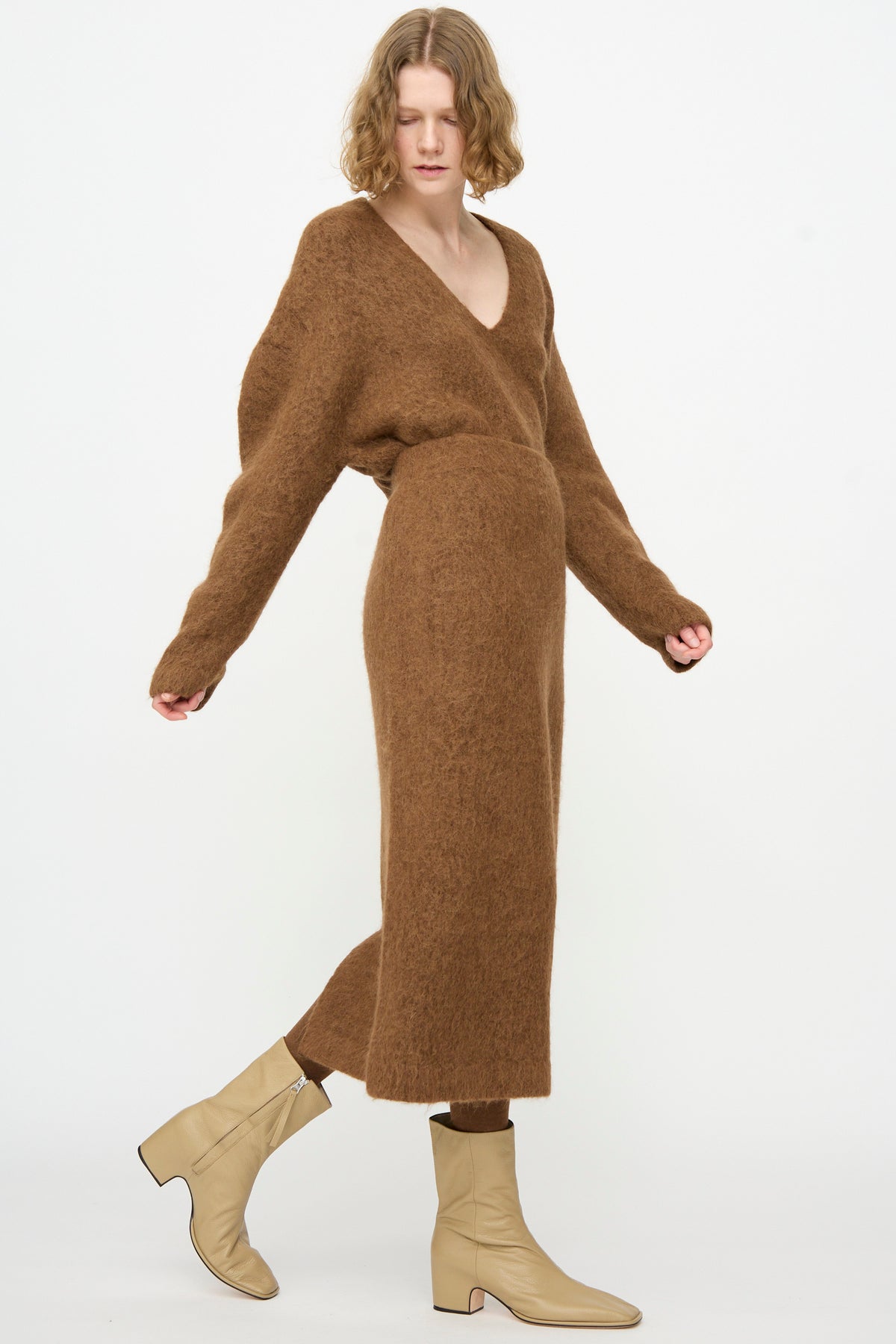 A person is wearing the Lauren Manoogian Brushed Pencil Skirt in Rust, styled with a long brown fuzzy V-neck knit top and beige ankle boots, standing against a plain white background.