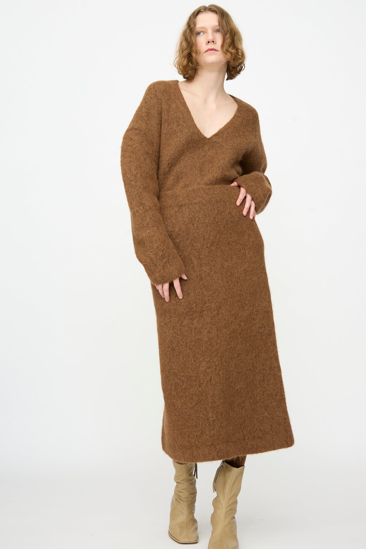 A person wearing the Lauren Manoogian Brushed Pencil Skirt in Rust—crafted in a refined, midi-length alpaca wool blend—stands against a plain white background, exuding cozy elegance.