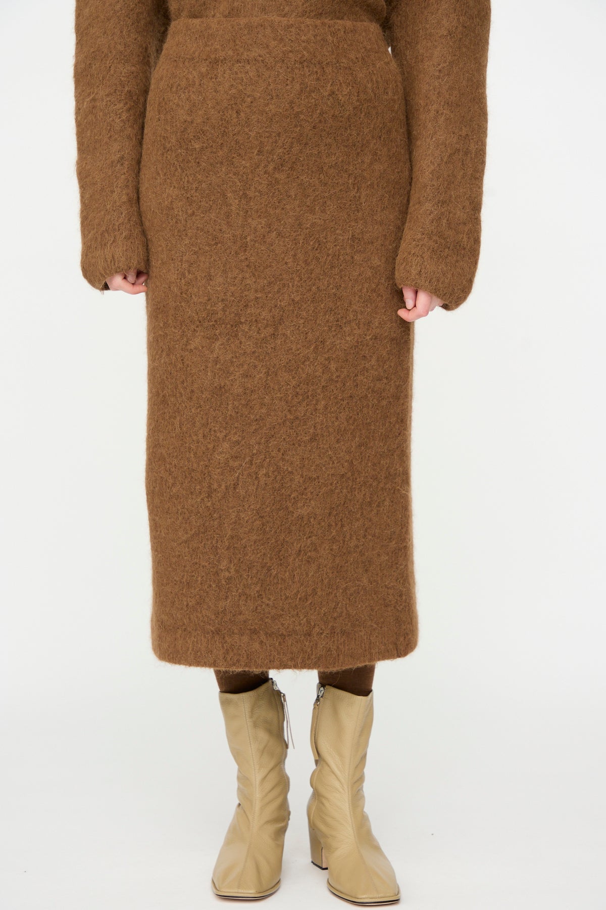 A person wearing the Lauren Manoogian Brushed Pencil Skirt in Rust with a matching top and tan mid-calf boots, standing against a plain white background.