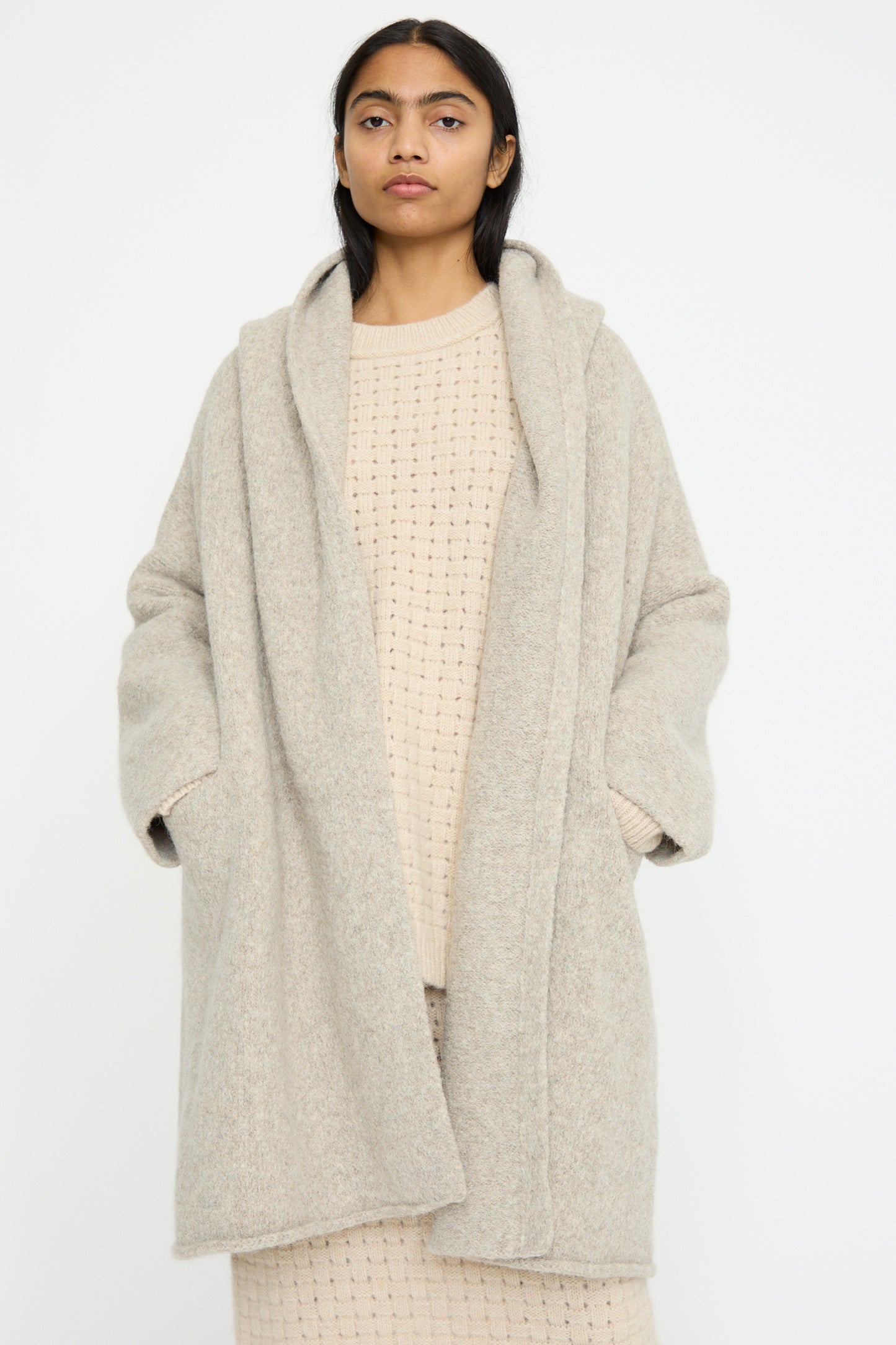 A person wears the Lauren Manoogian Capote Coat in Pebble, an alpaca wool textured open coat, over a matching relaxed fit knit outfit, standing against a plain background.