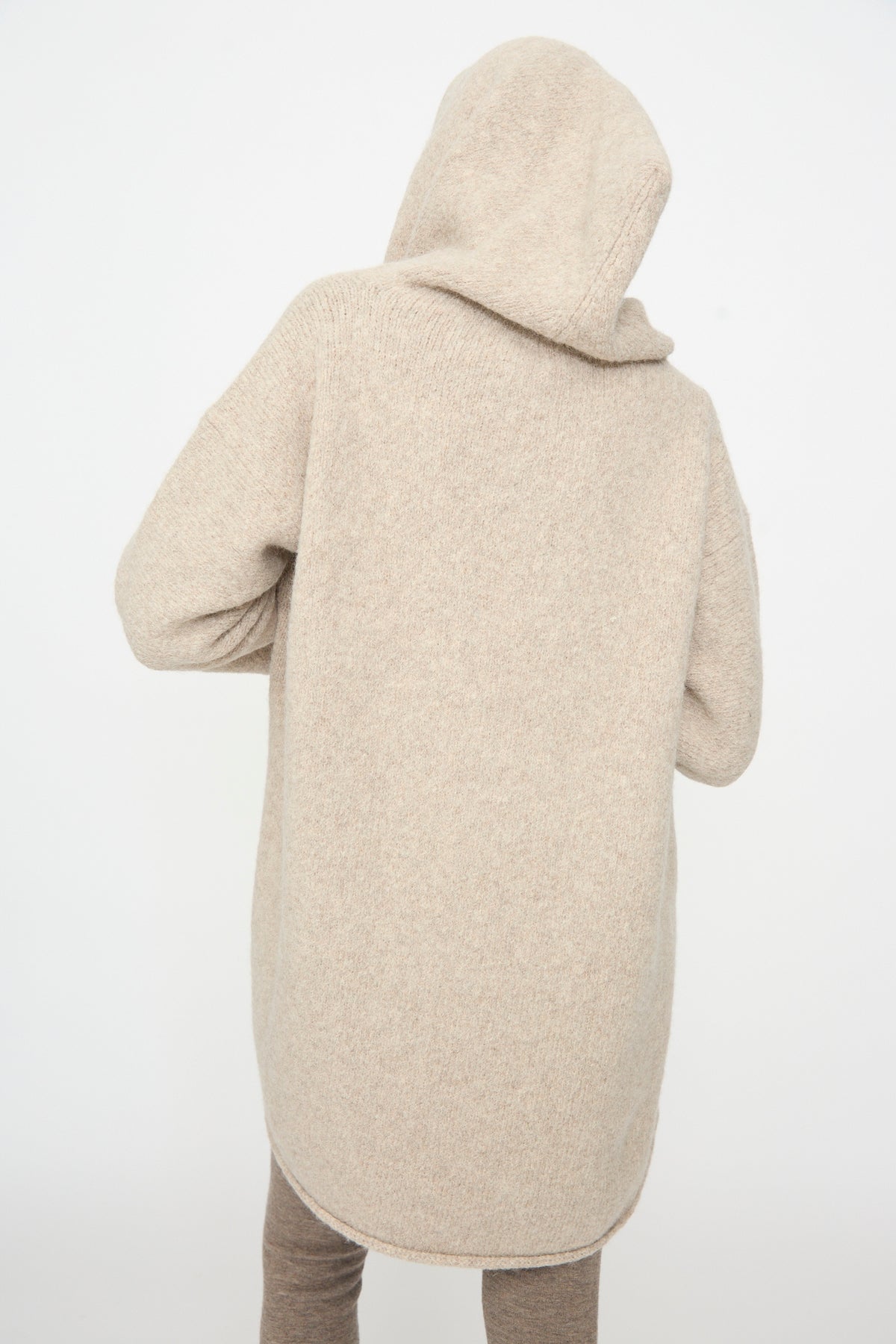 A person is seen from behind wearing the Lauren Manoogian Capote Coat in Pebble, standing against a plain white background and paired with brown pants.
