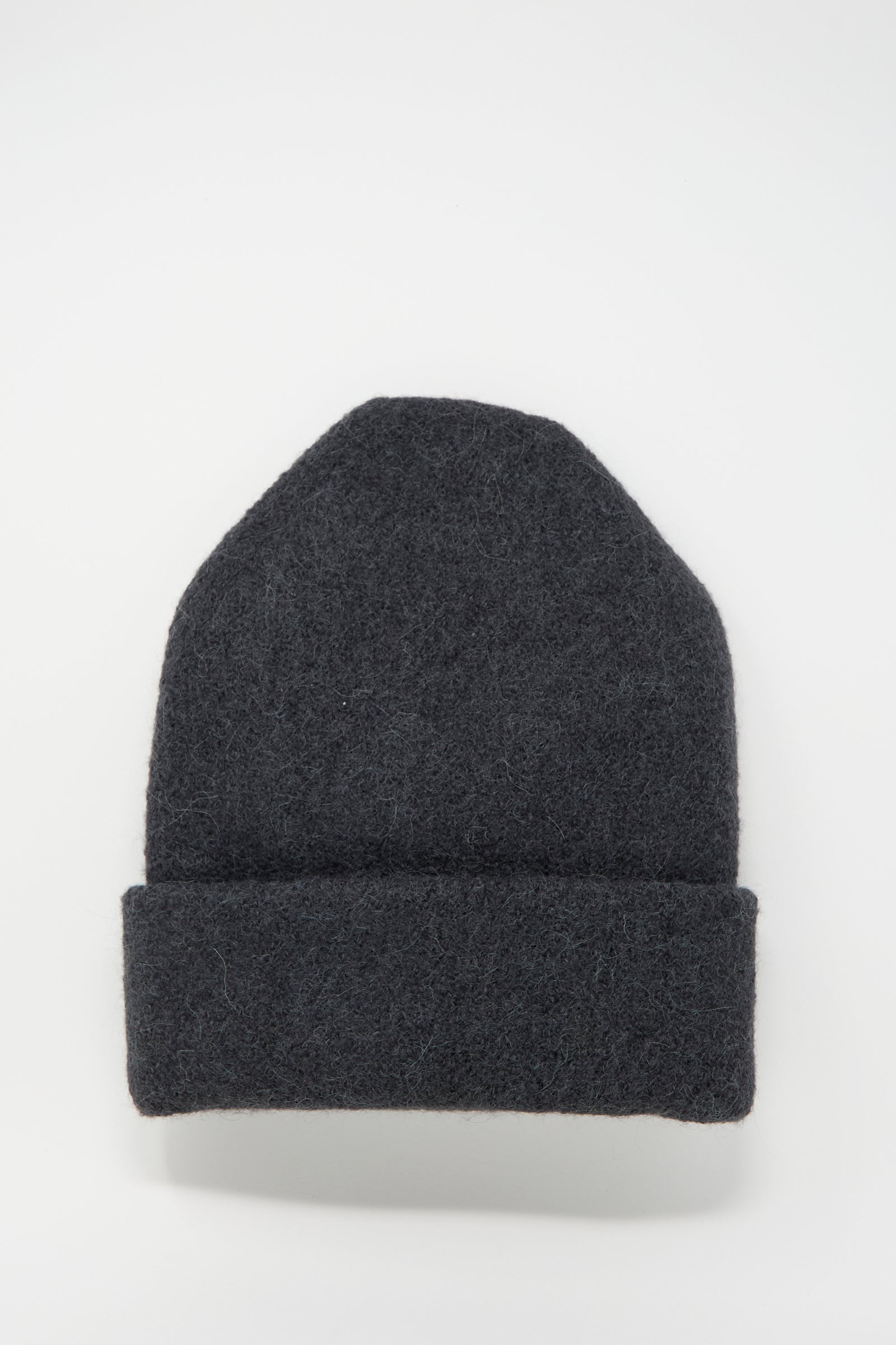 A Carpenter Hat in Ink by Lauren Manoogian, a dark grey alpaca beanie with a folded brim, handloomed and made in Peru, placed on a plain white background.