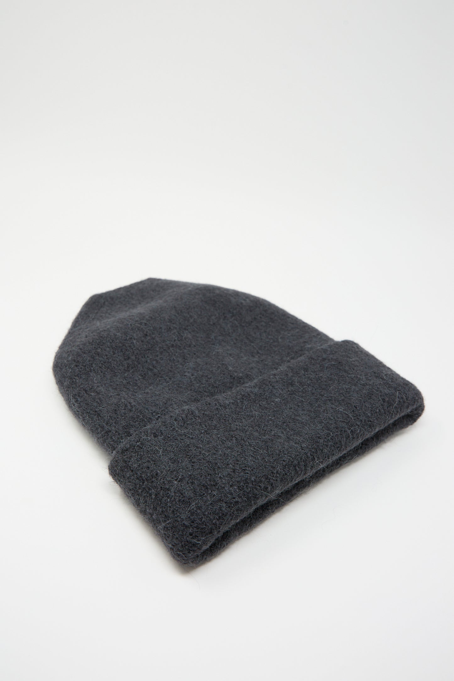 A Lauren Manoogian Carpenter Hat in Ink, handloomed and made from alpaca in Peru, is laid flat on a white background.