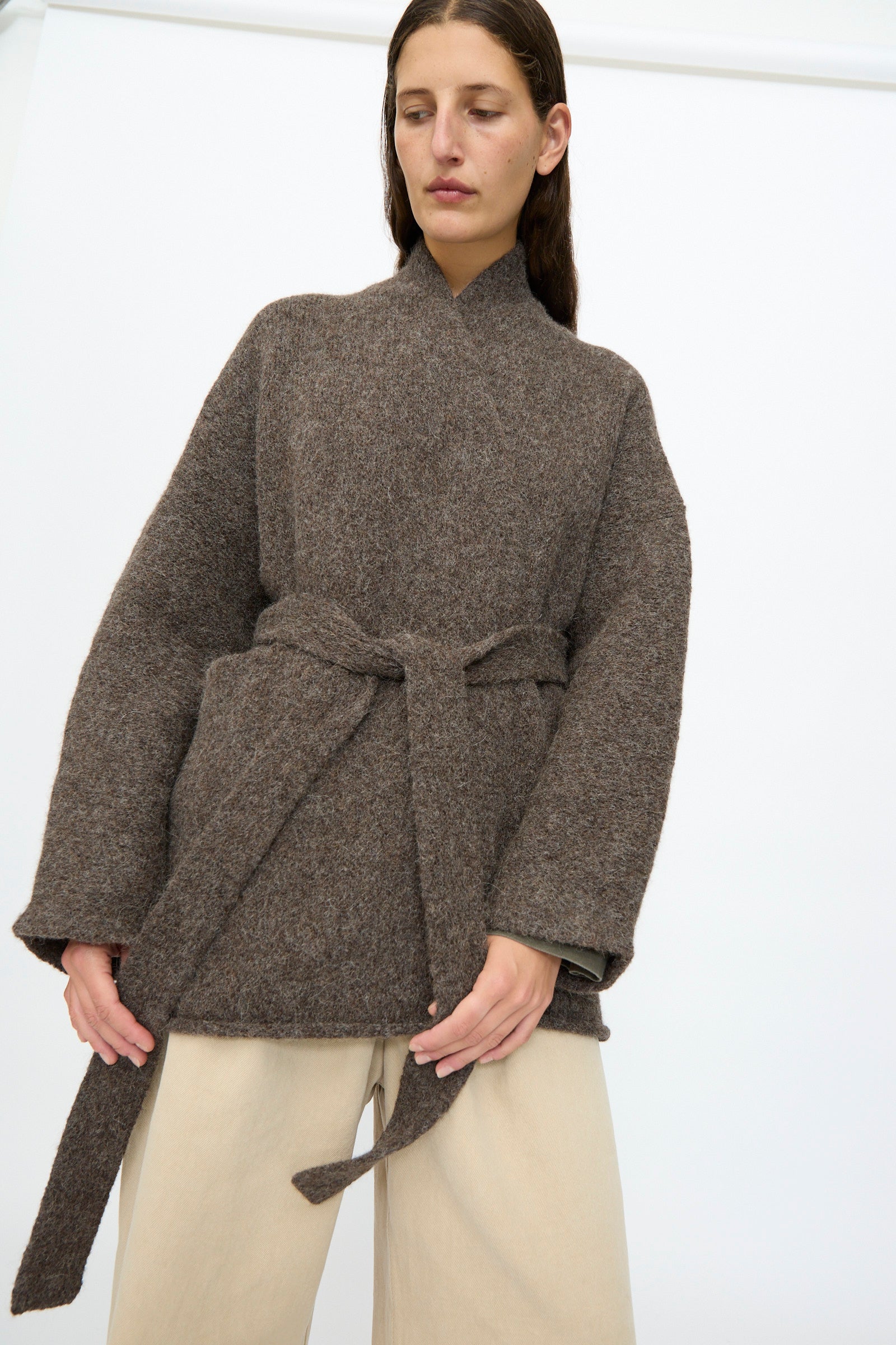 A person wearing the Lauren Manoogian Coto Cardigan in Patina and beige wide-leg, relaxed-fit pants stands against a plain white background.