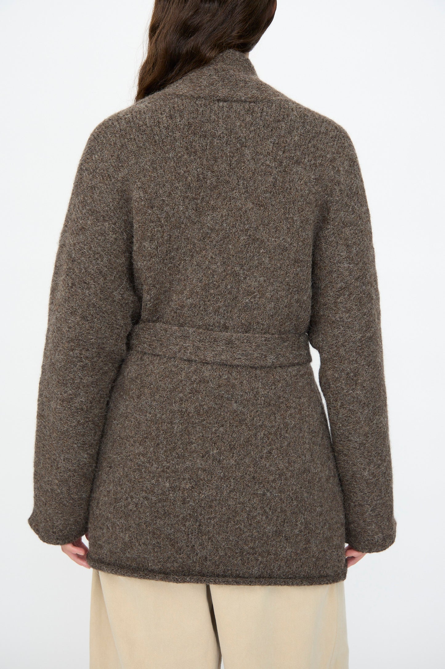 A person is shown from the back against a plain white background wearing the Lauren Manoogian Coto Cardigan in Patina and beige pants.