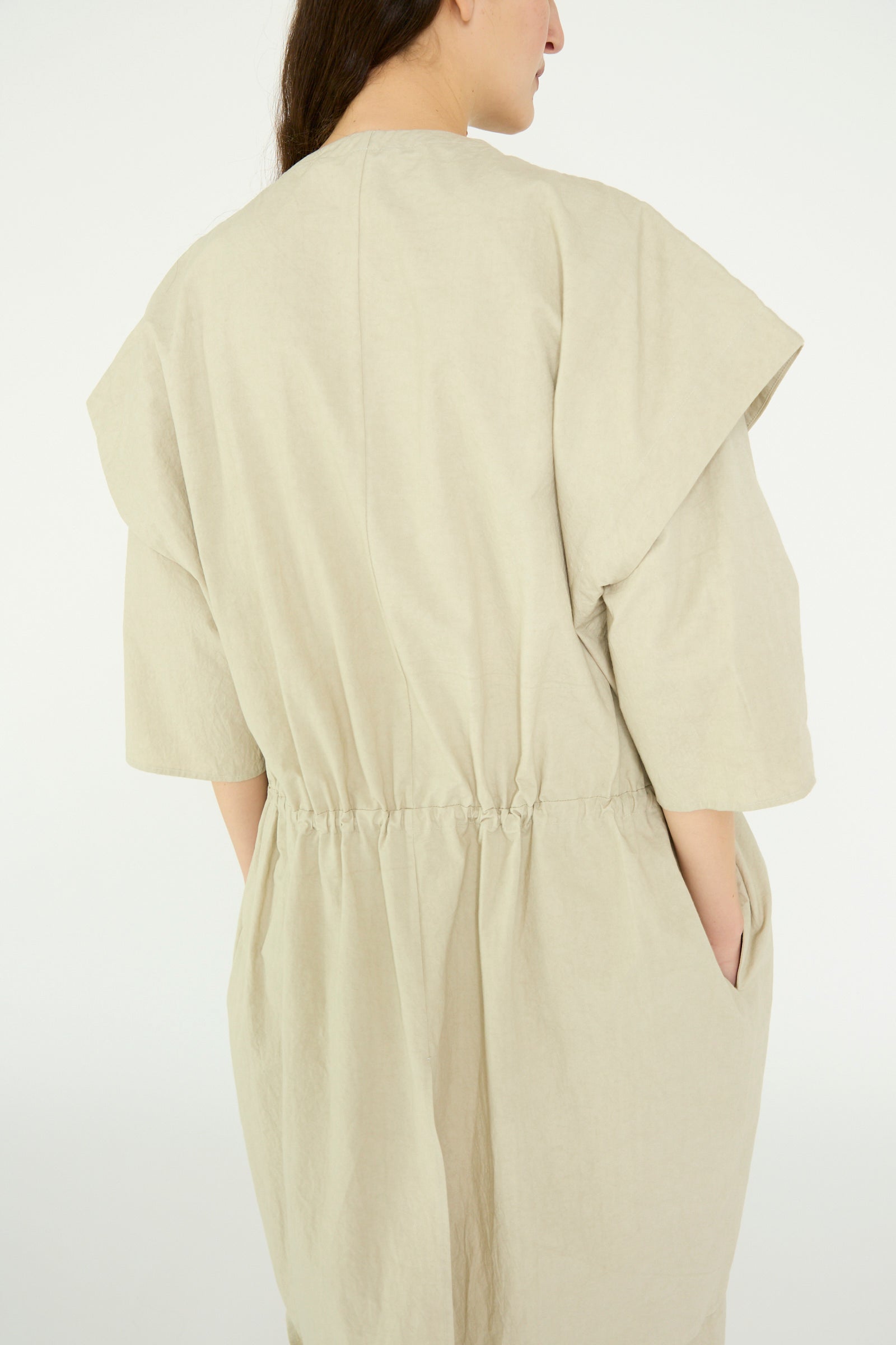 A person in a Lauren Manoogian Cowl Gilet in Plaster, showcasing an oversized fit, is viewed from the back against a plain light background.