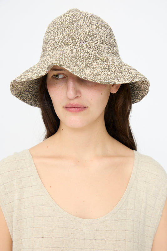 A woman with long dark hair wears the Lauren Manoogian Crochet Brim Hat in Rock Marl and a sleeveless light top, looking slightly to the side against a plain background.