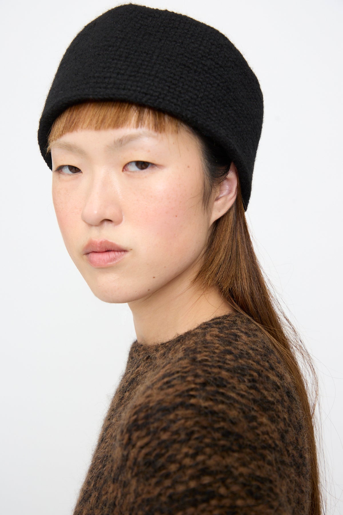 A person wearing a black merino wool Lauren Manoogian Crochet Toque in Black.