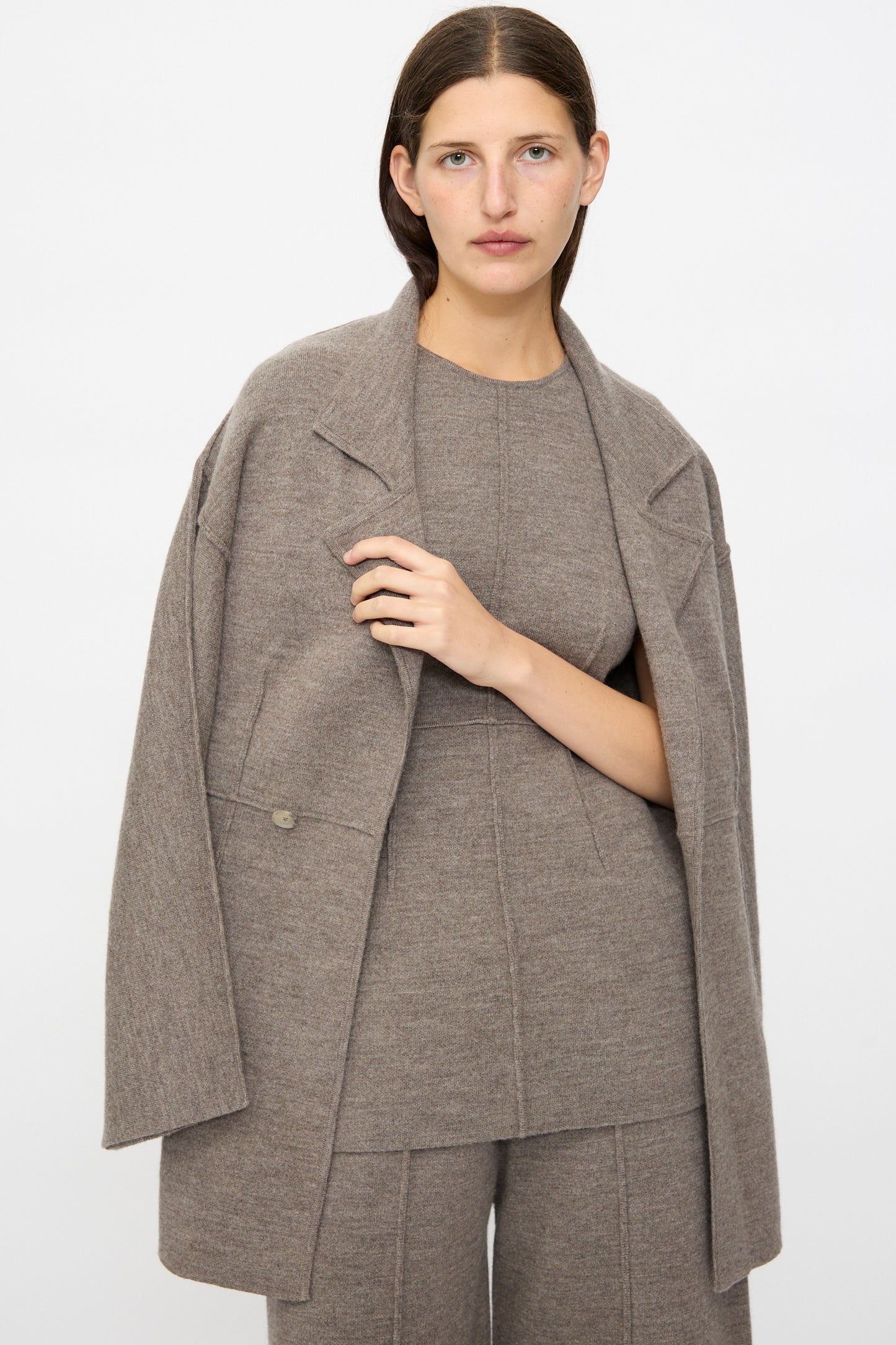 A person with straight brown hair wears the Lauren Manoogian Double Knit Blazer in Cinder over a matching top and pants, standing against a plain light background.