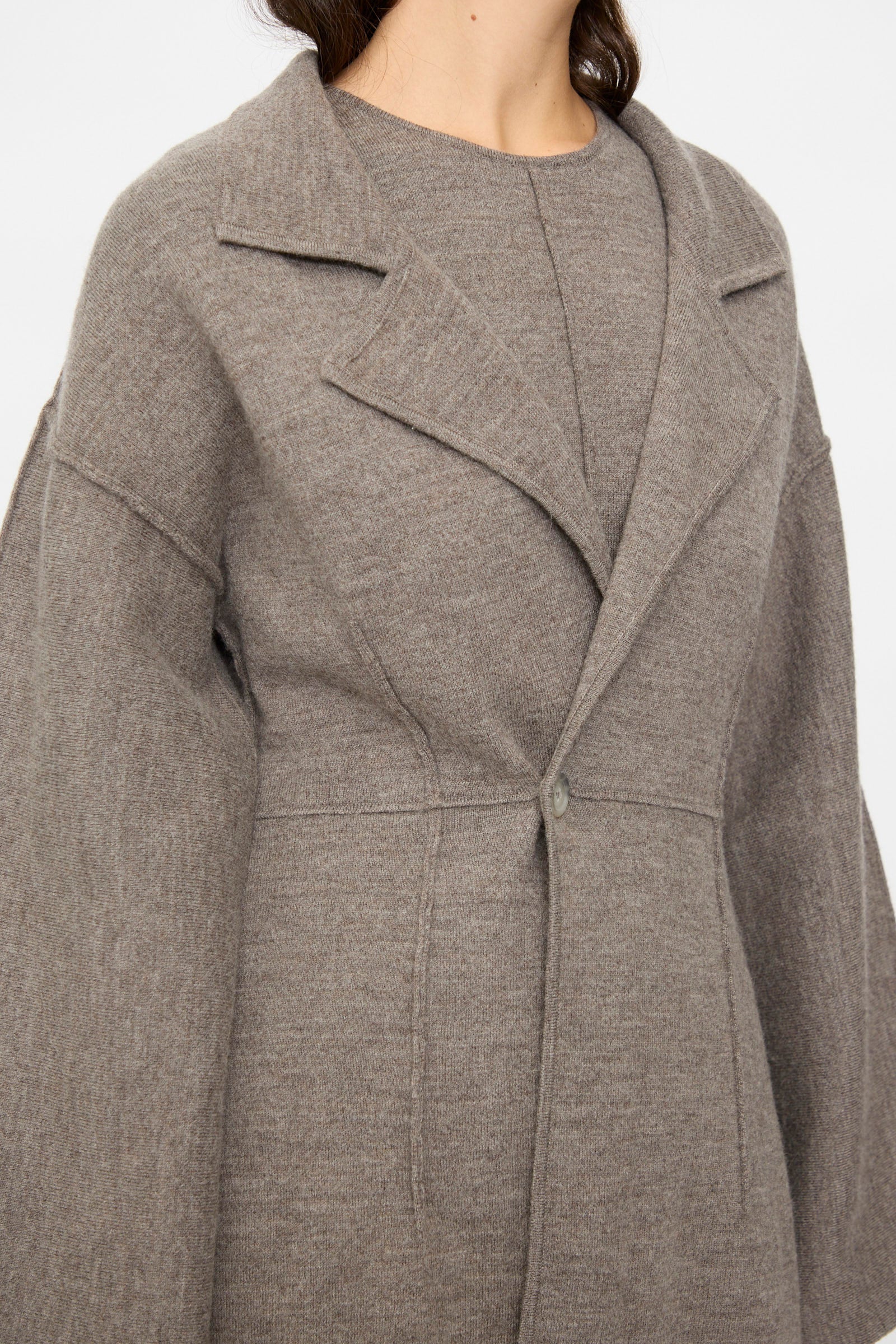 A person wearing the Lauren Manoogian Double Knit Blazer in Cinder, featuring a structured silhouette with a notched collar and single button closure, styled over a matching top.