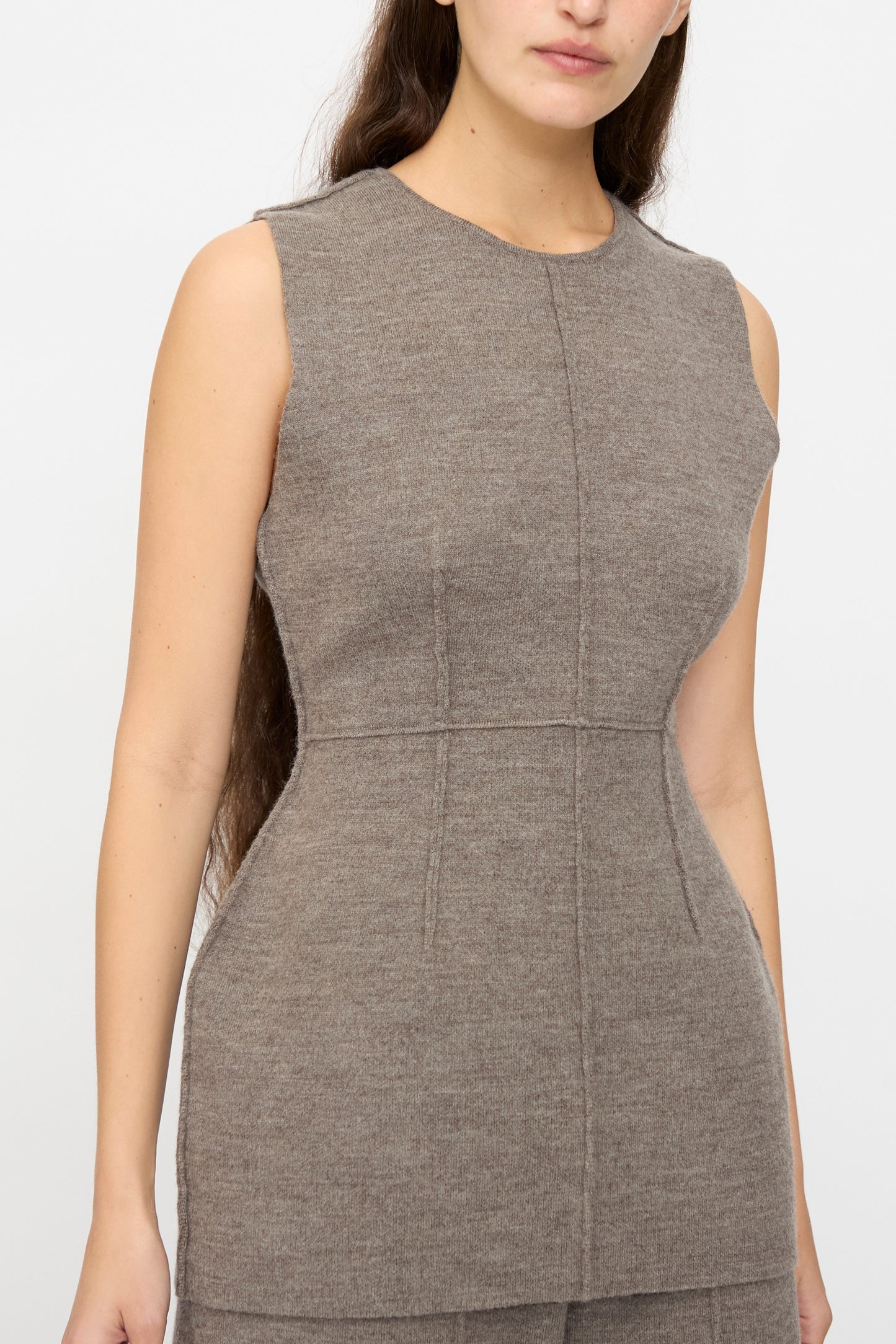 A woman wears the Lauren Manoogian Double Knit Bodice in Cinder, a sleeveless, fitted taupe top with visible seams, standing against a plain light background.