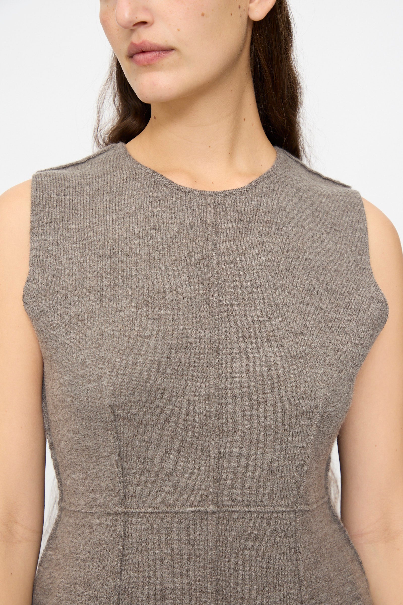 A woman wears the Lauren Manoogian Double Knit Bodice in Cinder, a sleeveless knit top. Her face is partly visible, and her long hair cascades over one shoulder.