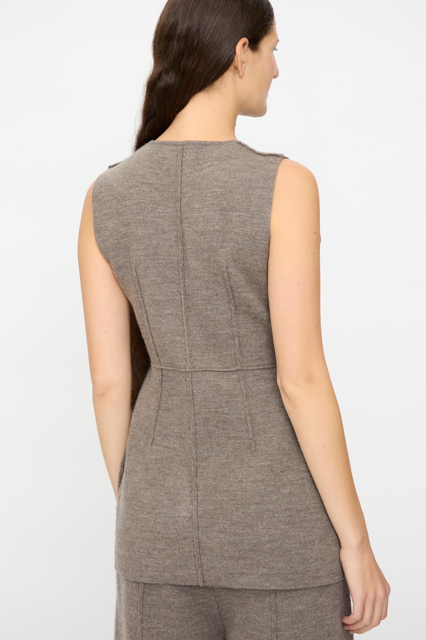 A woman with long brown hair is seen from the back wearing the Lauren Manoogian Double Knit Bodice in Cinder, paired with matching pants, against a plain light background.